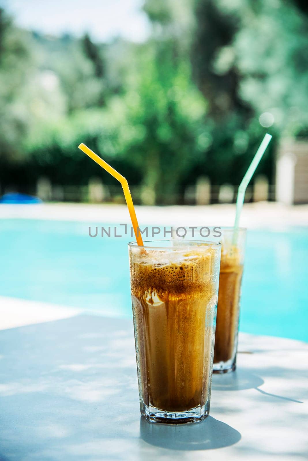 Two glass of iced frappe near the swimming pool.
