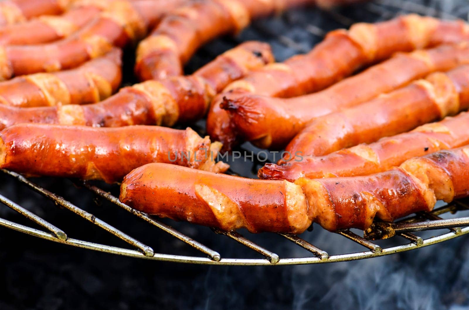 Grilled sausages bbq on outdoor picnic. Fresh tasty sausage preparing for summer barbecue.