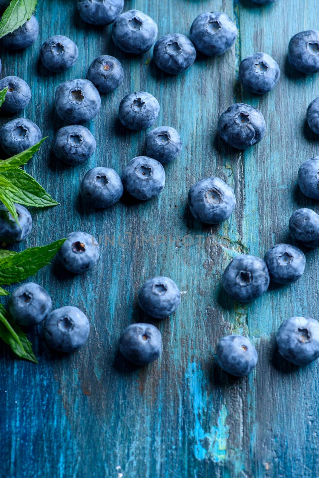 Fresh blueberries on blue rustic wooden table pattern. Healthy organic seasonal fruit background design. Organic food blueberries and mint leaf for healthy lifestyle.