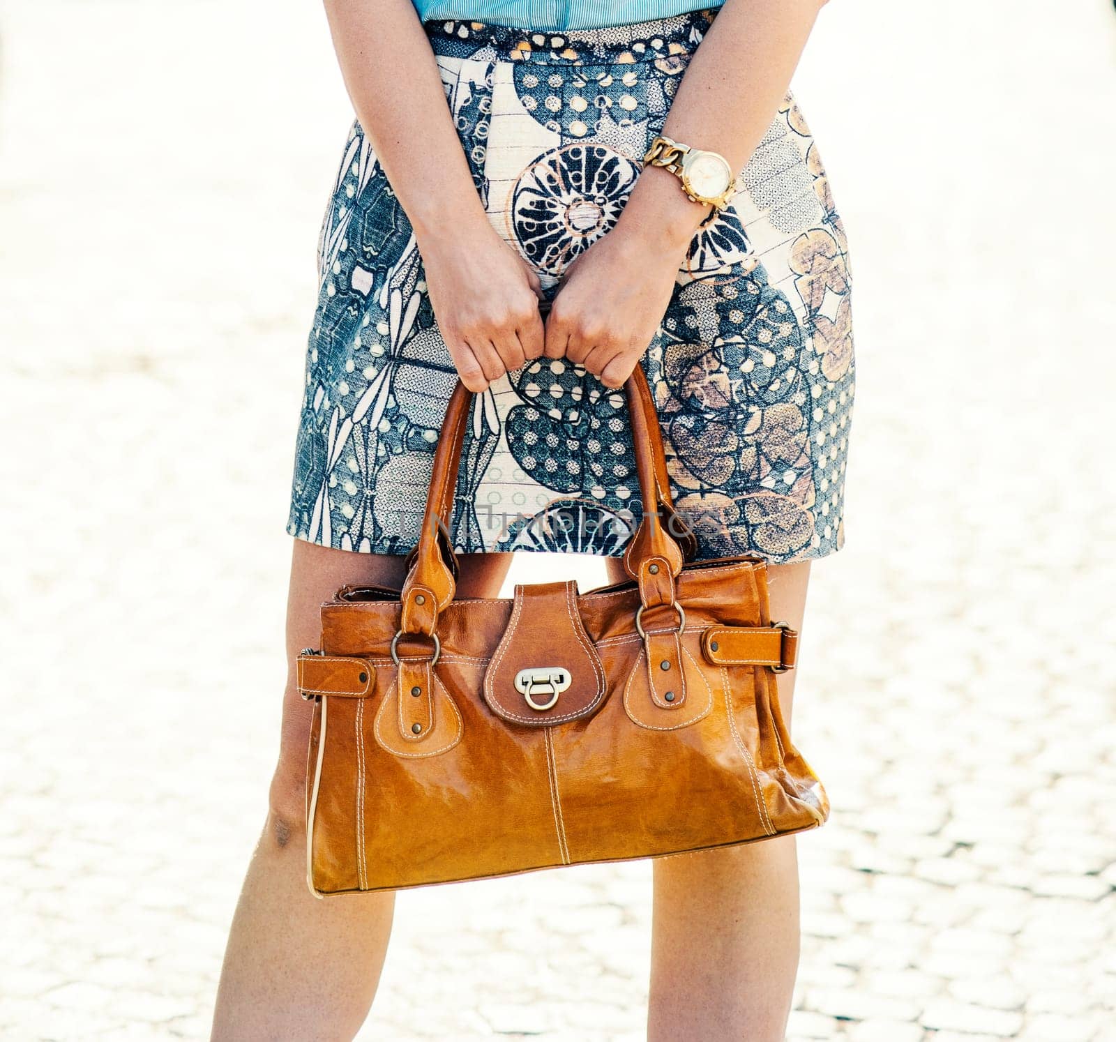 Street fashion and beauty concept. Stylish lady holding luxury natural leather handbag in hands. Closeup of modern trendy bag in female hands. Woman in smart and chick clothing.