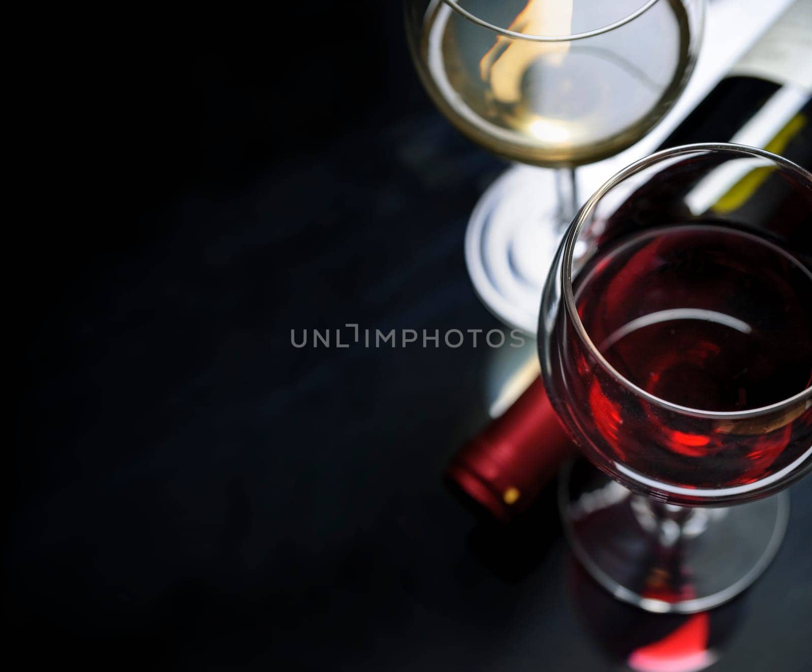 Glass of red and white wine on black background. Wine list design menu with copyspace. Alcohol beverage card backdrop.