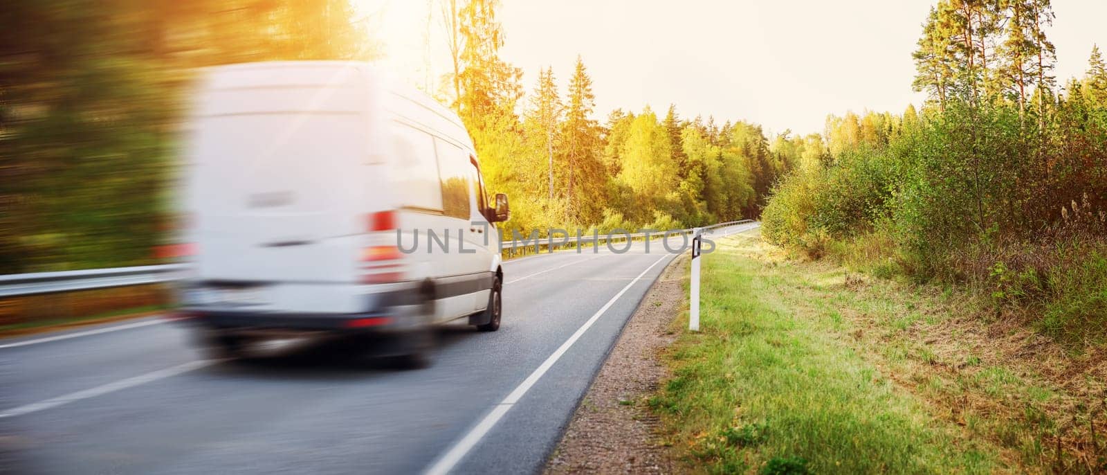 Van moving on the country road in natural park on the sunset. Concept of import and export.