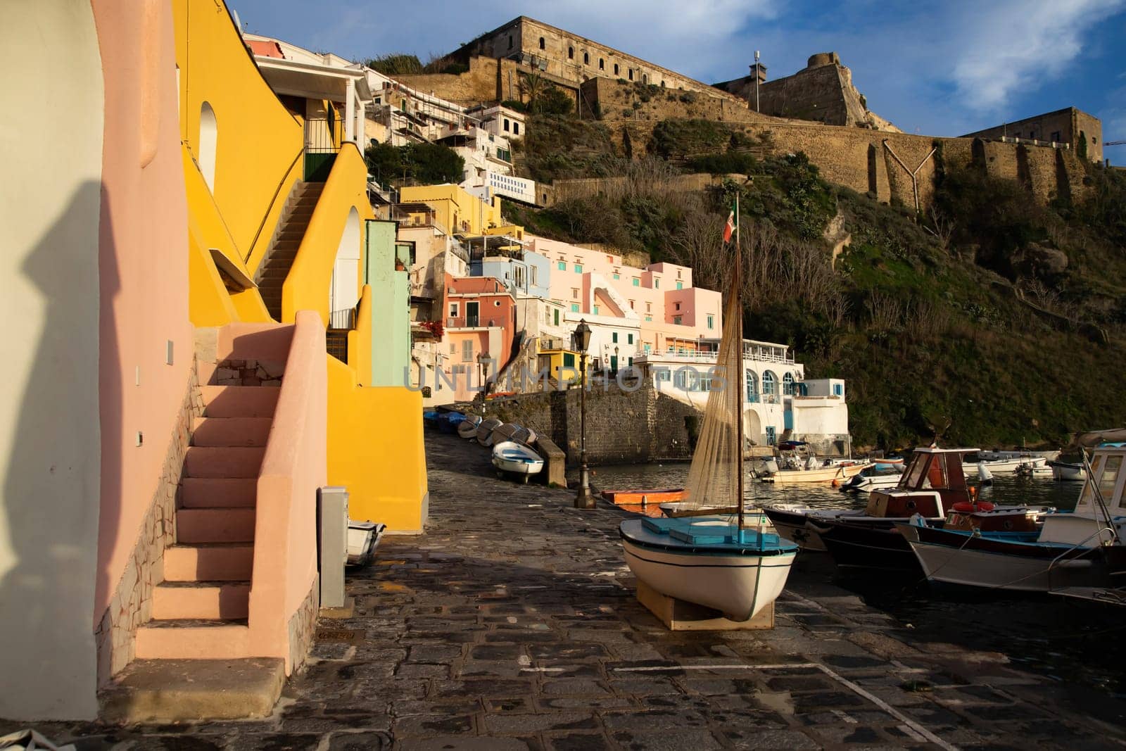 View of the Port of Corricella with lots of colorful houses on a sunny day in Procida Island, Italy.
