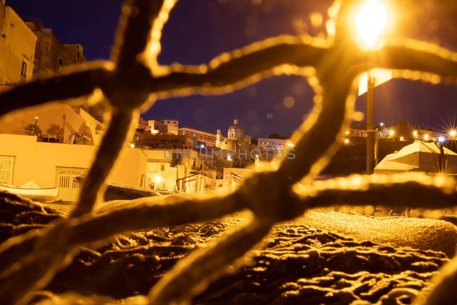 Fishing nets the Port of Corricella with lots of colorful houses after sunset in Procida Island, Italy.