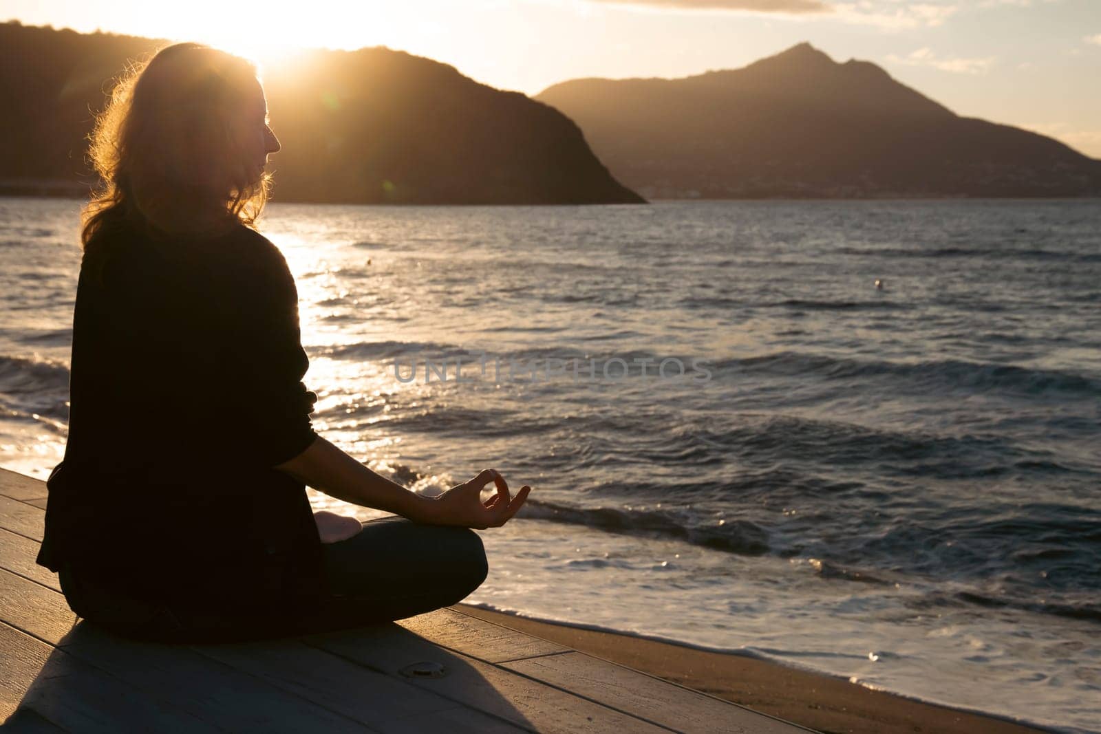 Woman in a yoga pose at sunset at the beach. Mindfulness and mental health concept.