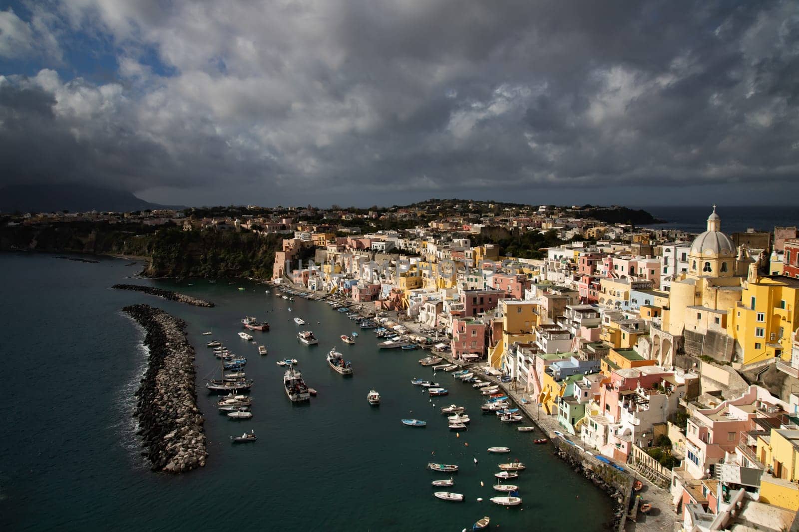 View of the Port of Corricella with lots of colorful houses on a sunny day in Procida Island, Italy.