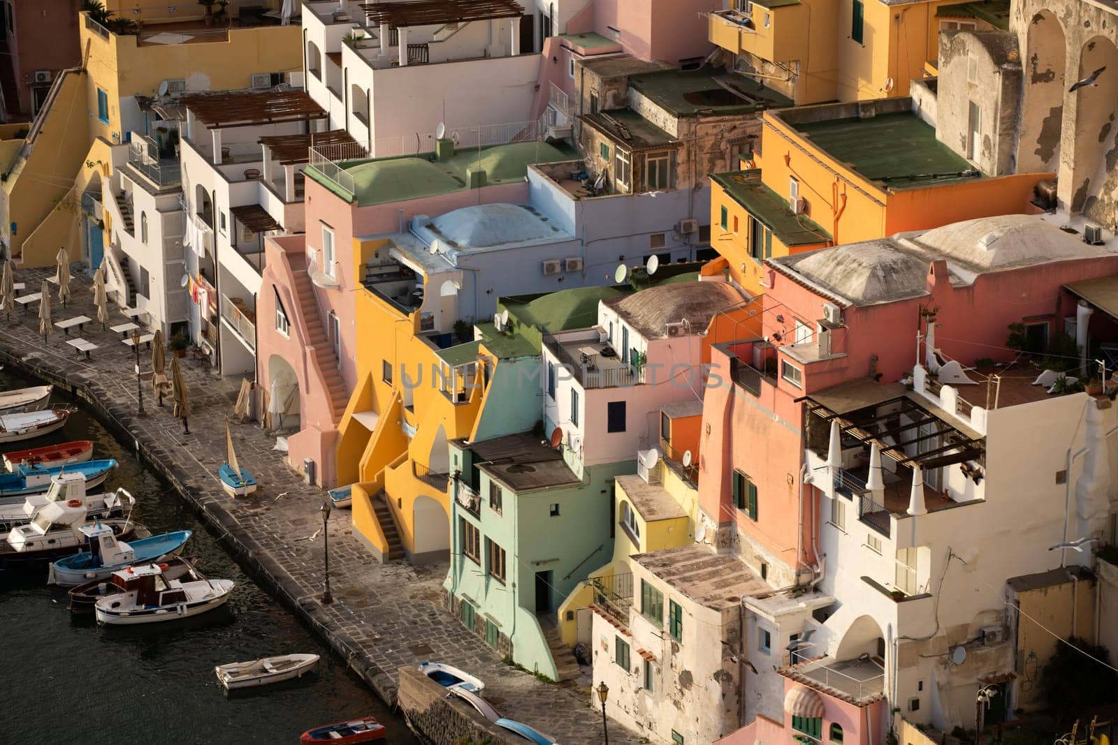 View of the Port of Corricella with lots of colorful houses in the sunset, Procida Island, Italy.