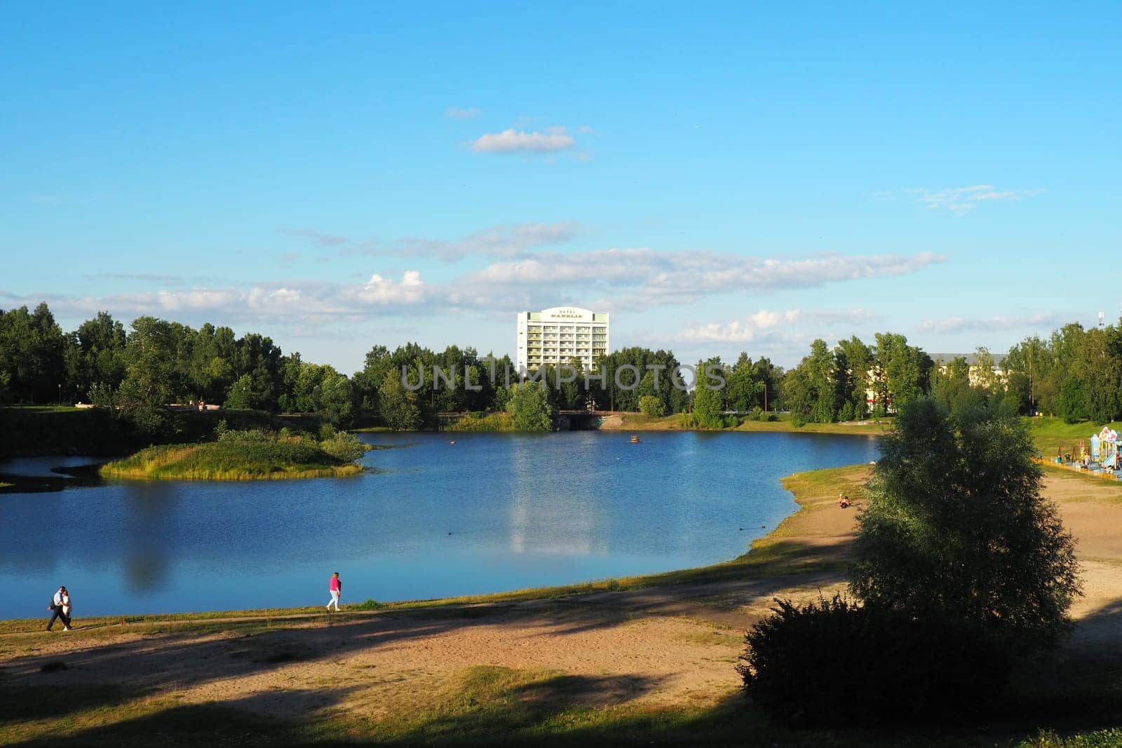 Mouth, floodplain and terraces of the Lososinka River, Petrozavodsk, Republic of Karelia August 3, 2022. Sunny windless evening. City sandy beach. Passers-by people with children walk. Hotel Karelia.
