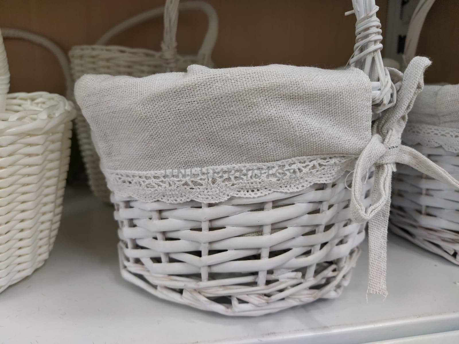 Wicker decorative baskets on a shelf in a store. Pretty baskets painted white. Textile bag. Stylish gift for Easter. Decor element of the interior of an apartment, a country house or a spring garden