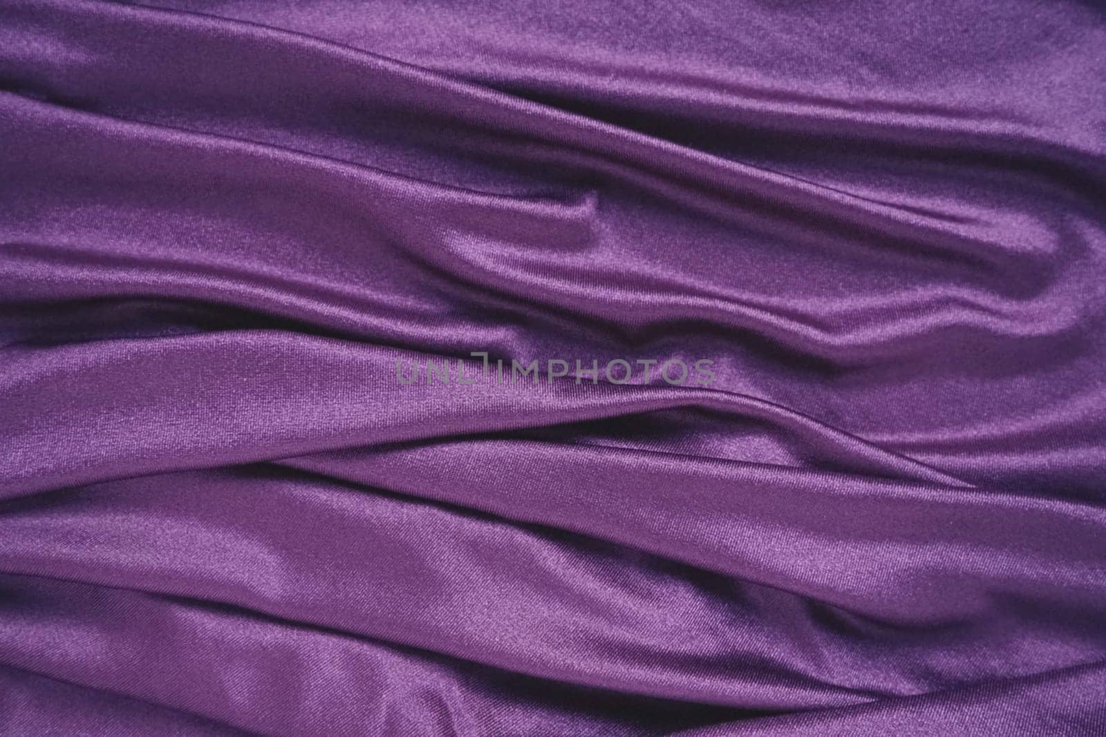 Velour fabric, similar to silk. Textiles in a folds and beautiful waves. Purple, pink, magenta shades on the drapery. Sewing material for evening dresses, furniture upholstery, curtains and interior