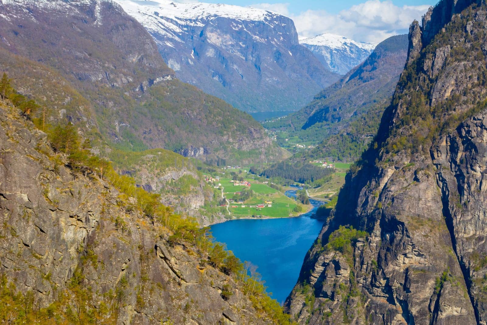 View on Norwegian fjord village in the distance, looking through rocks and mountains. Travel and tourism in Norway.
