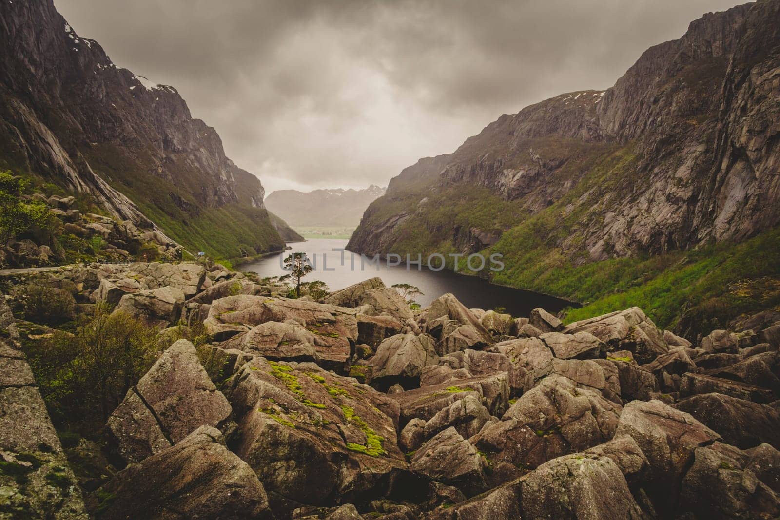 Beautiful fjord view in Norway with rock boulders and valley on a clouded day.