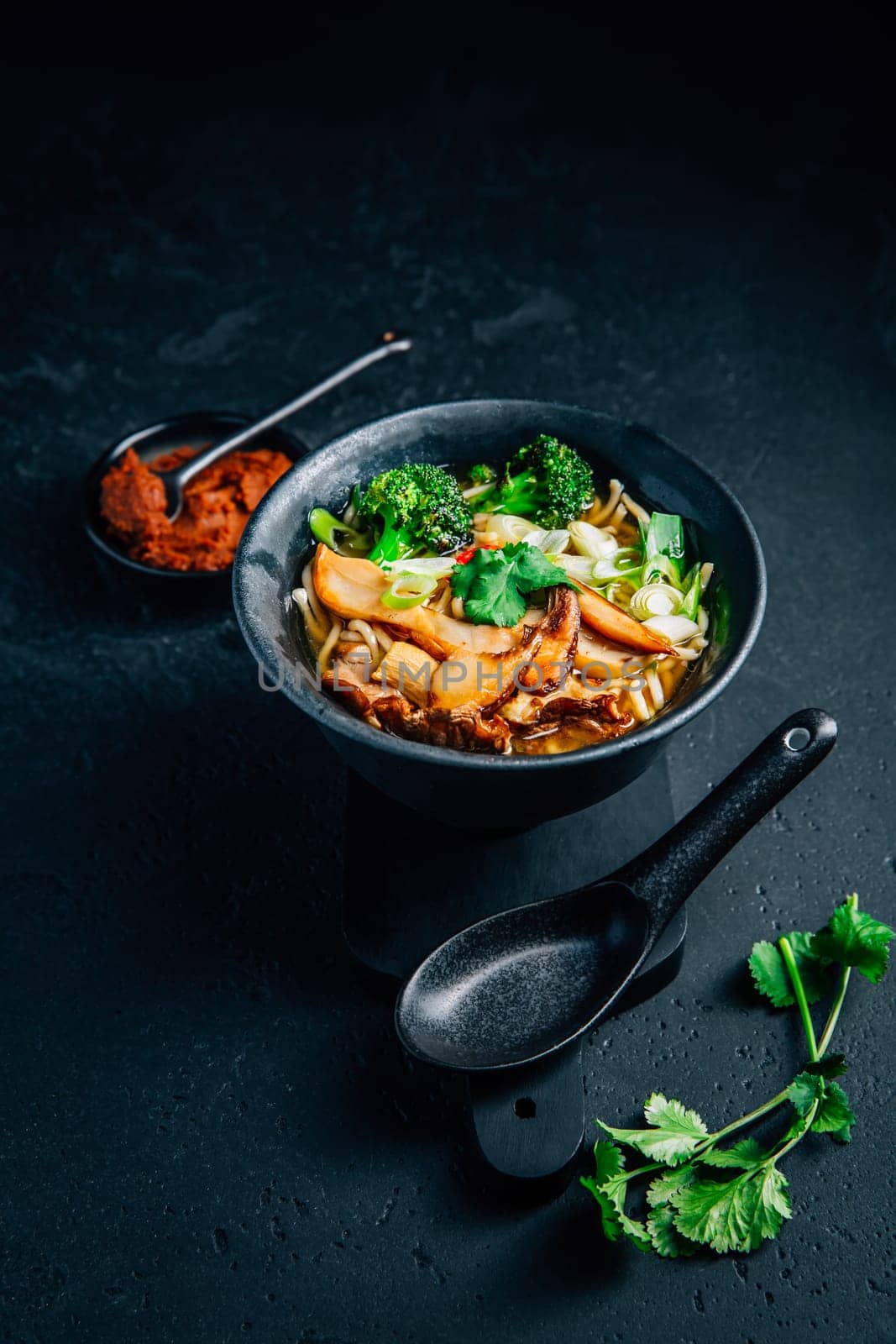 Vegan miso or ramen soup with mushrooms and vegetables on black background