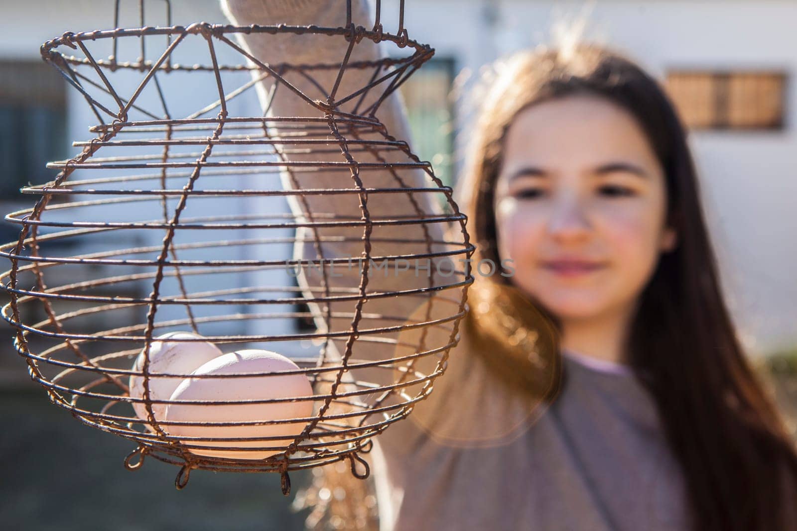 Child girl holds a rusty wire egg cup. Country style. Selective focus