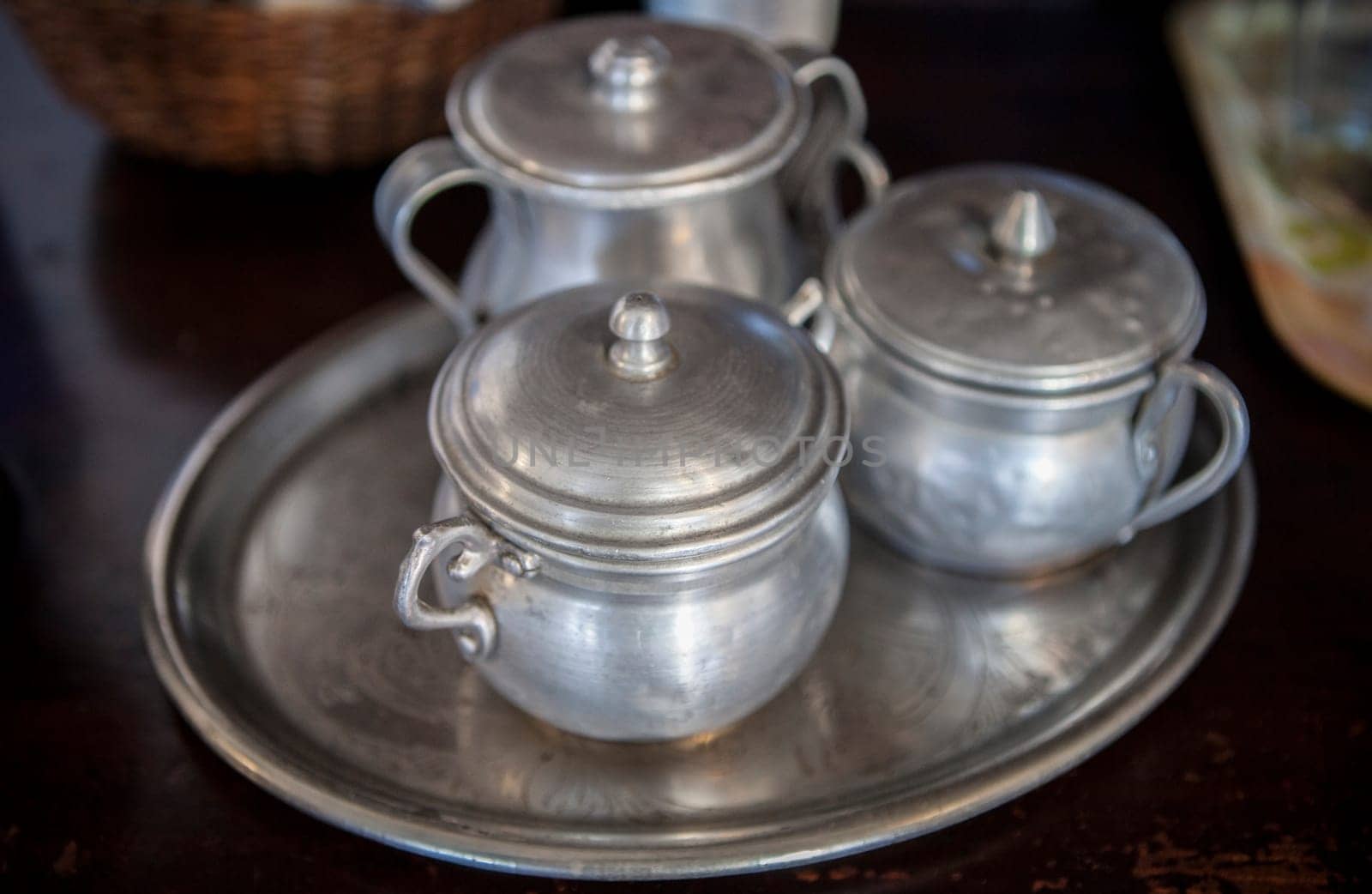 Old aluminum sugar bowls on a tray. Selective focus