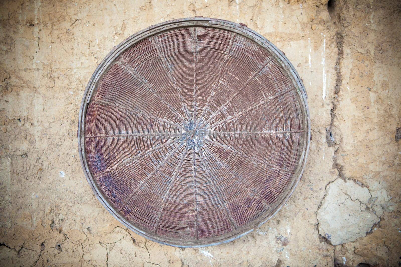 Old rusty sieve attacched over barn adobe wall. Selective focus