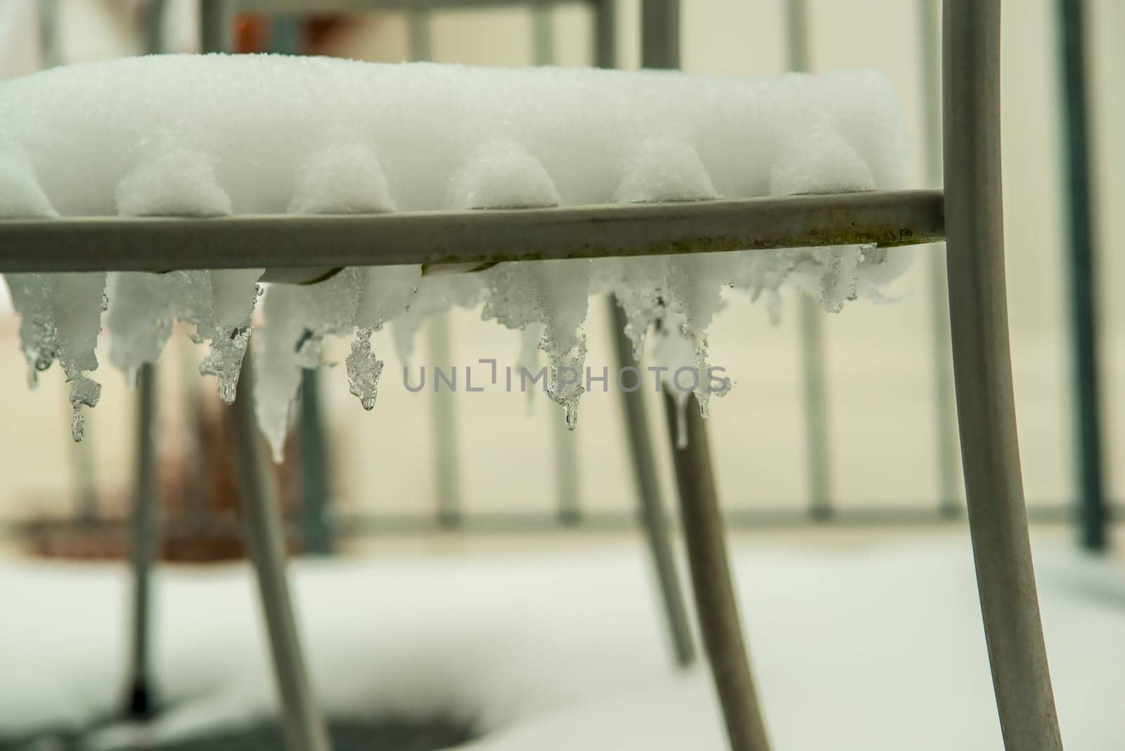 icicles and snow on a chair on a balcony