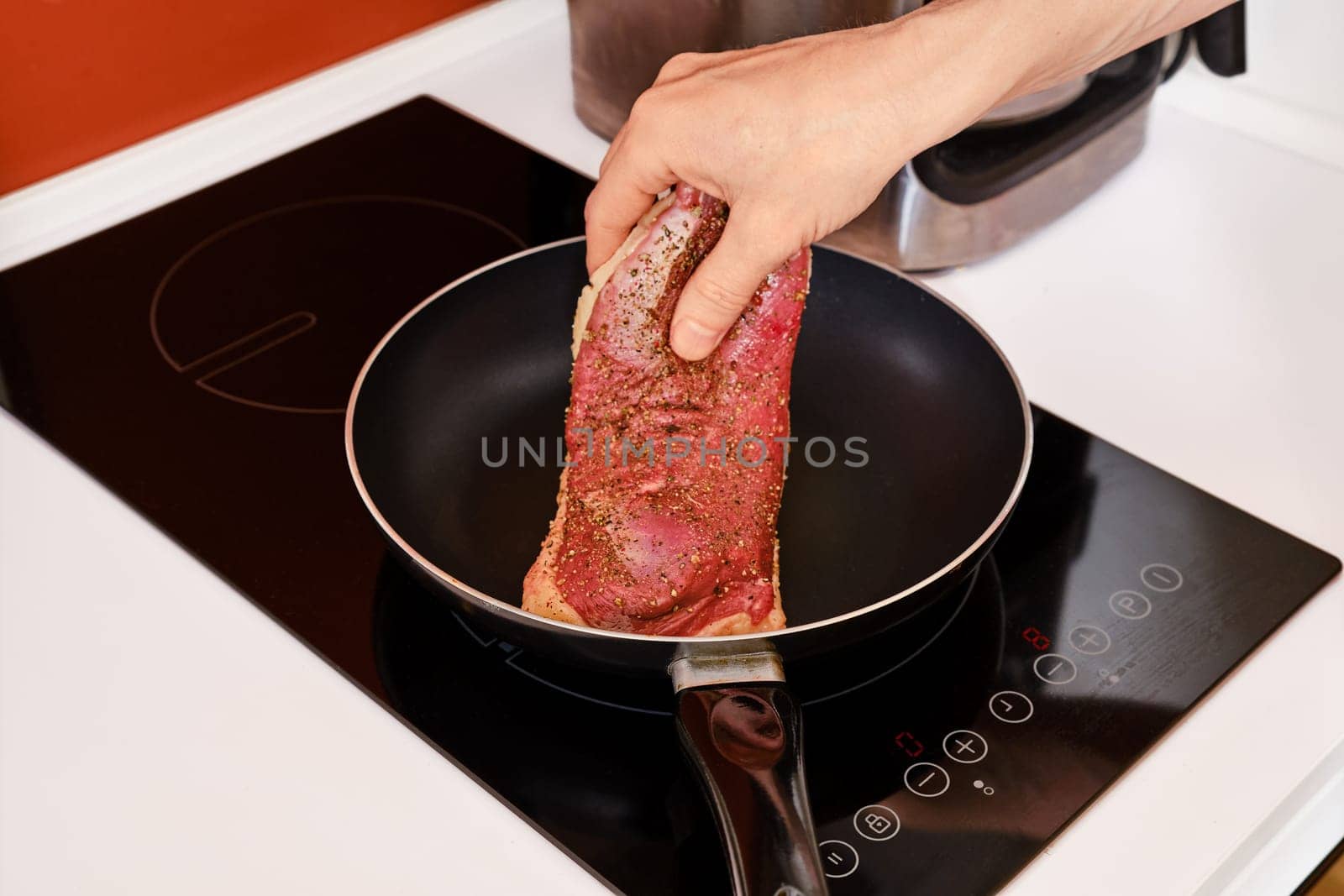Placing duck breast in a hot frying pan, closeup view