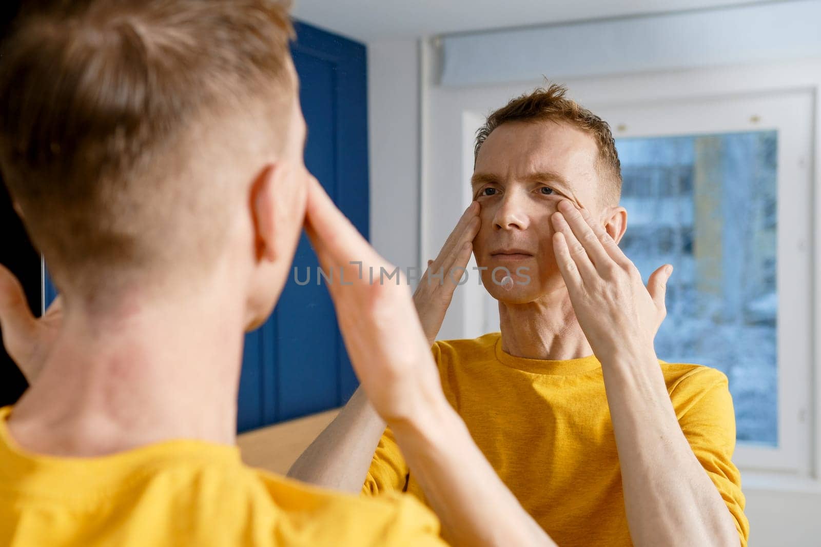 Mature adult man massaging face rubbing cream into skin
