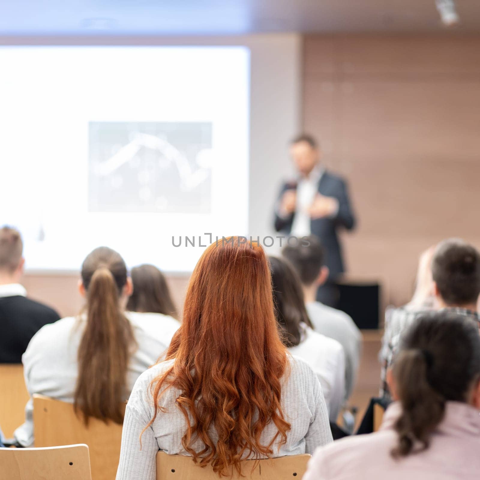 Speaker giving a talk in conference hall at business event. Rear view of unrecognizable people in audience at the conference hall. Business and entrepreneurship concept