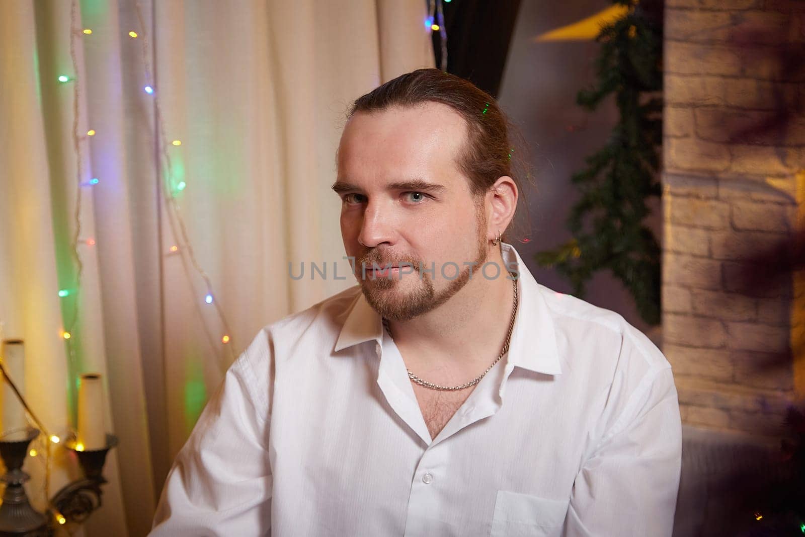 A person enjoys a holiday celebration surrounded by Christmas decorations and soft lights, creating a joyful ambiance.