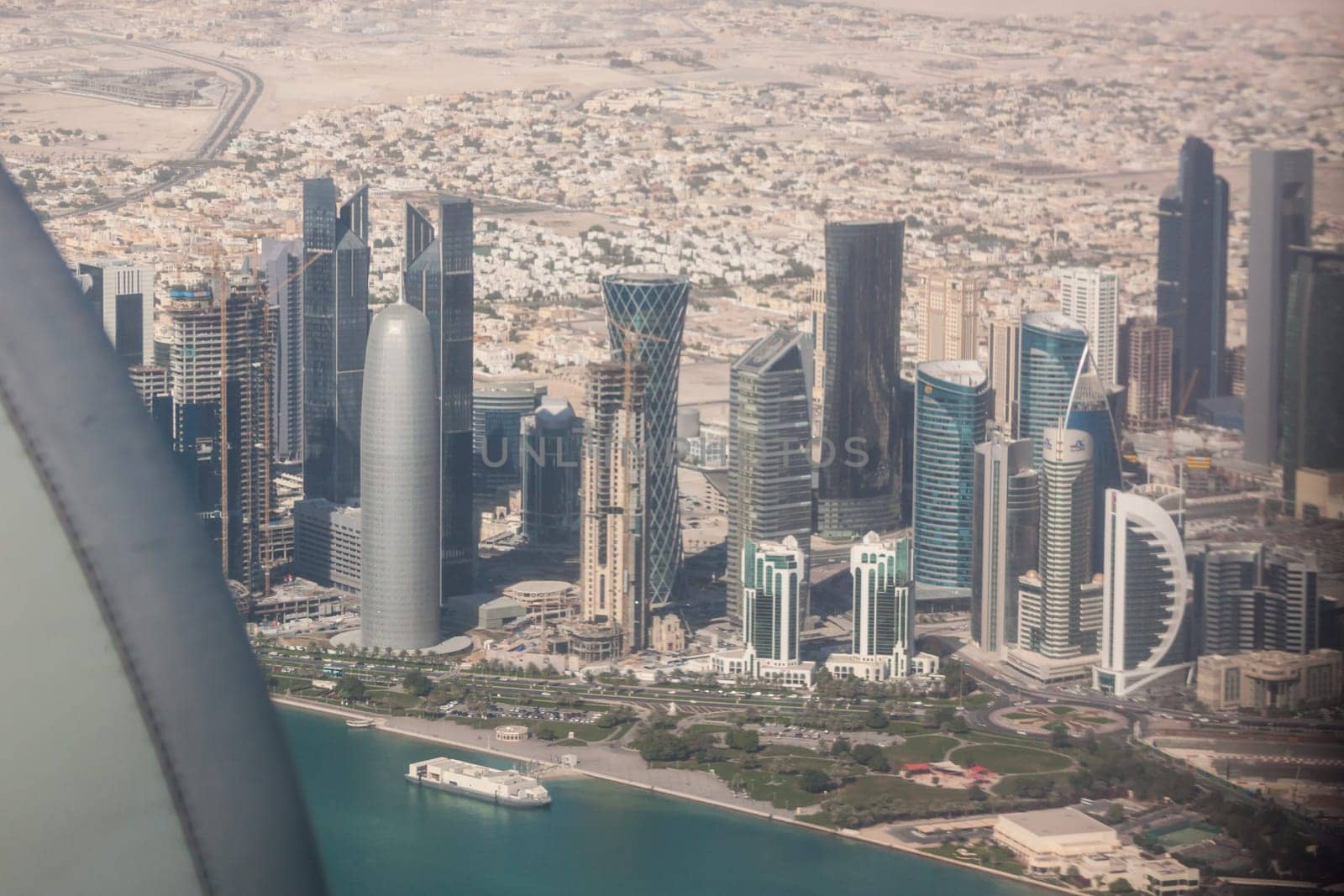 Aerial view of Doha through plane window, capital of Qatar in the Persian Gulf