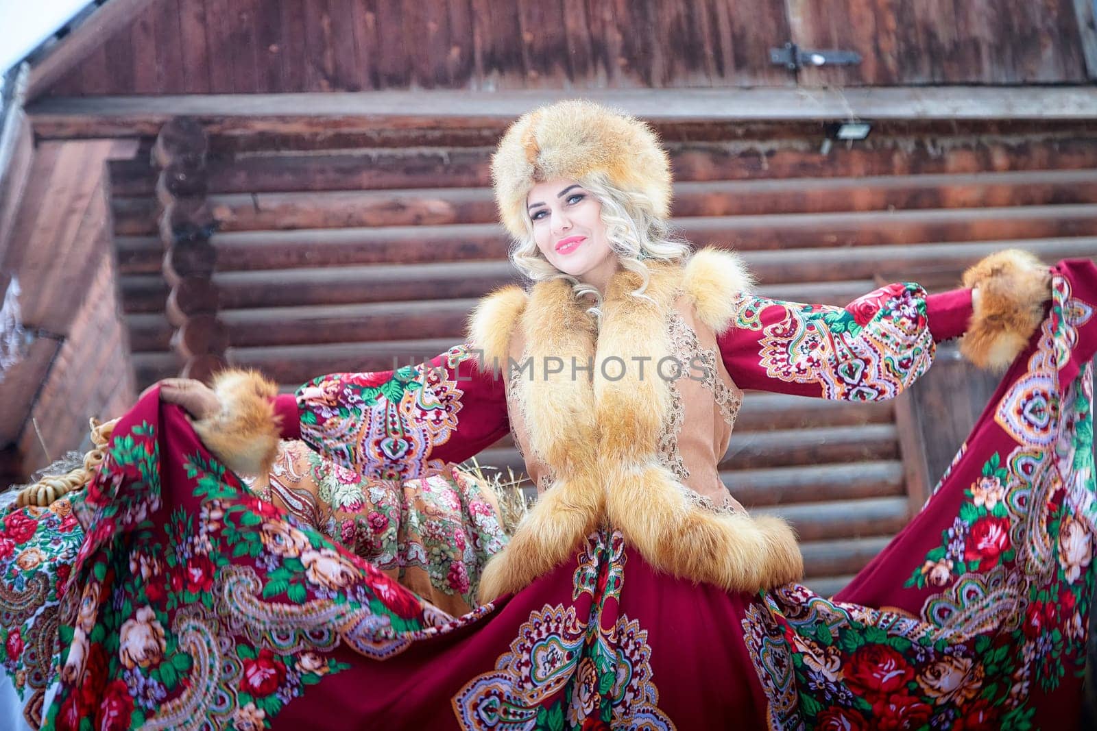 A Russian girl in a vibrant national dress poses with a horse during the Maslenitsa holiday festivities in winter.