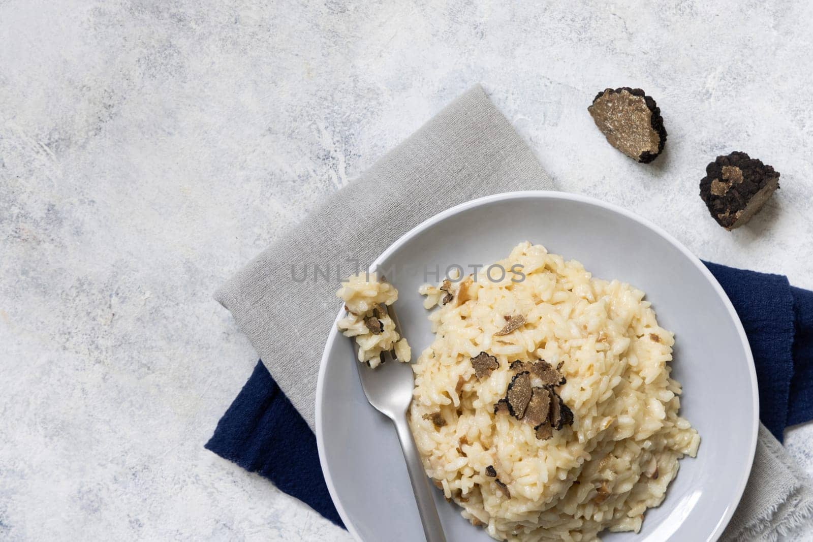Risotto with wild porcini mushrooms and black truffles from Italy served in a plate top view on white table, copy space. Eating Italian gourmet cousine