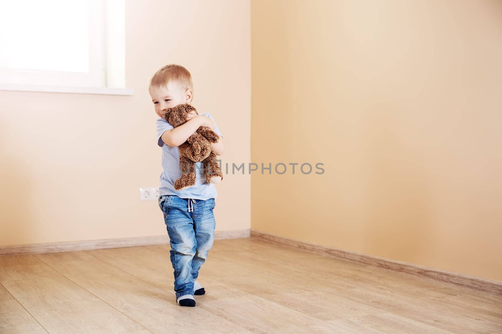 Cute boy sitting standing in empty room. Concept of family relocation, rental apartment and home ownership.