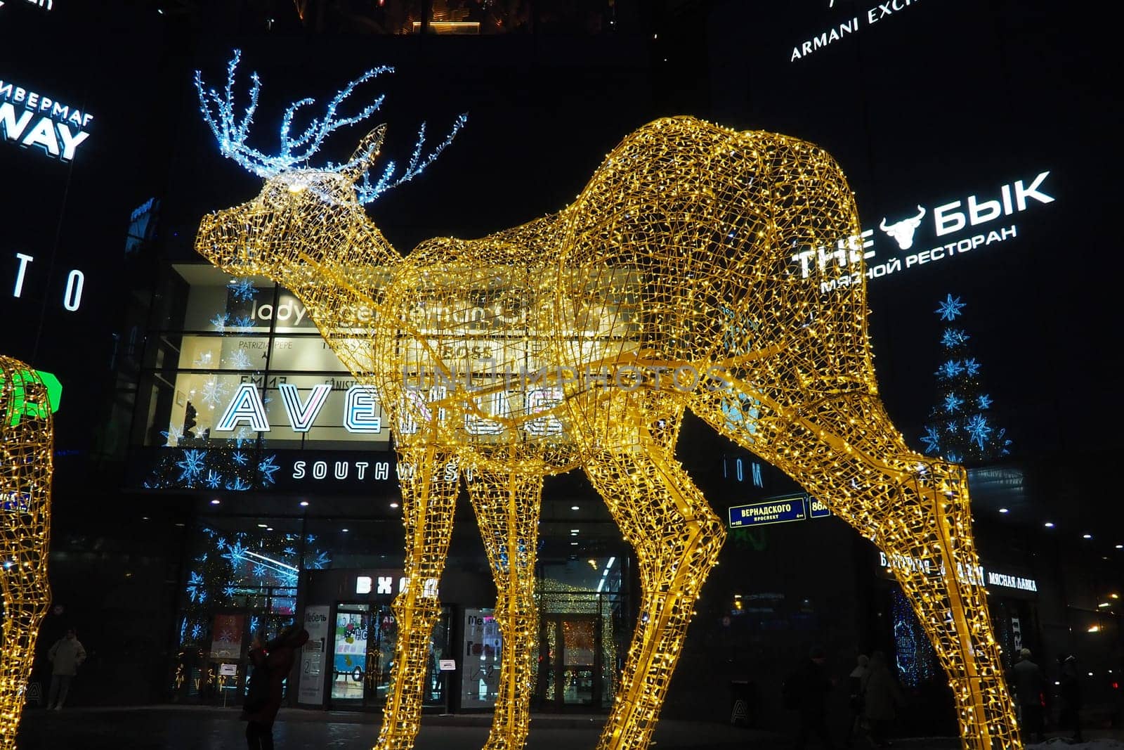 Moscow, Russia, January 17 2023 Metro Yugo-Zapadnaya. Christmas decorations in front of the mall. New year street decorations in the form of sparkling deer. Deer figure made from yellow gold garlands