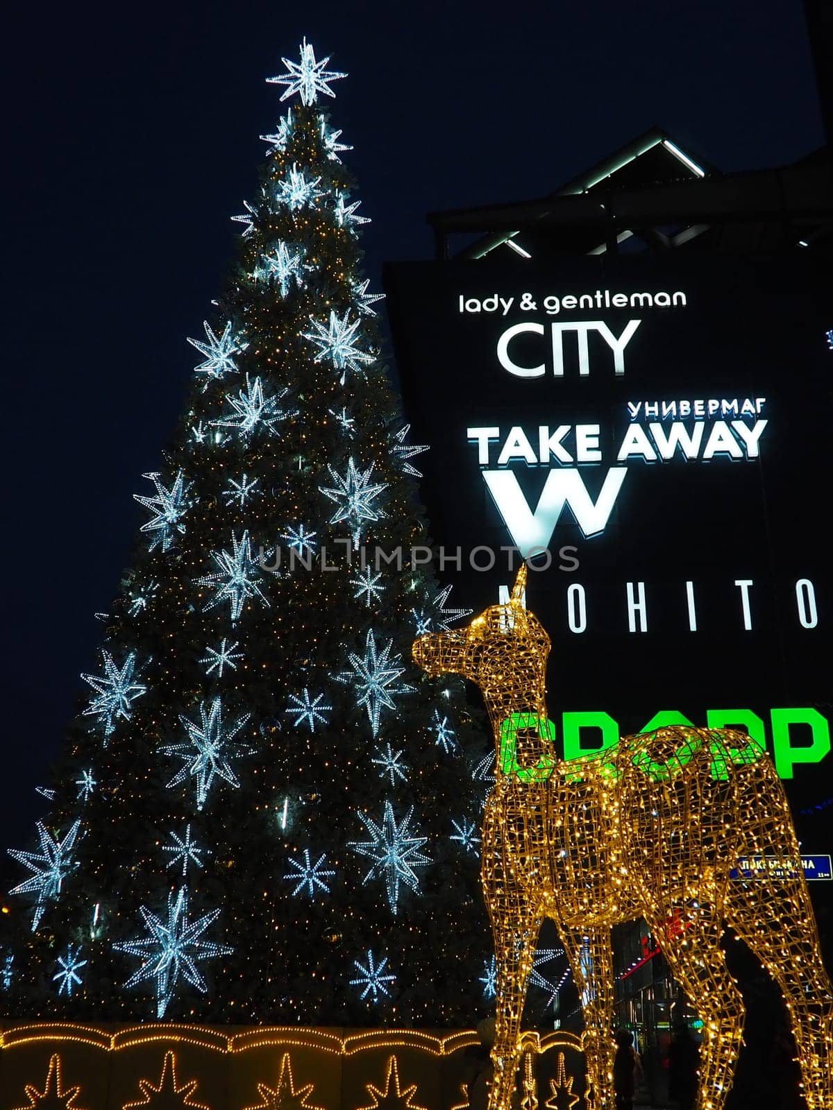Moscow, Russia, January 17 2023 Street Christmas tree with snowflakes and festive balls. Metro Yugo-Zapadnaya. Christmas decorations in front of the mall. Silver stars, snowflakes and golden deer.
