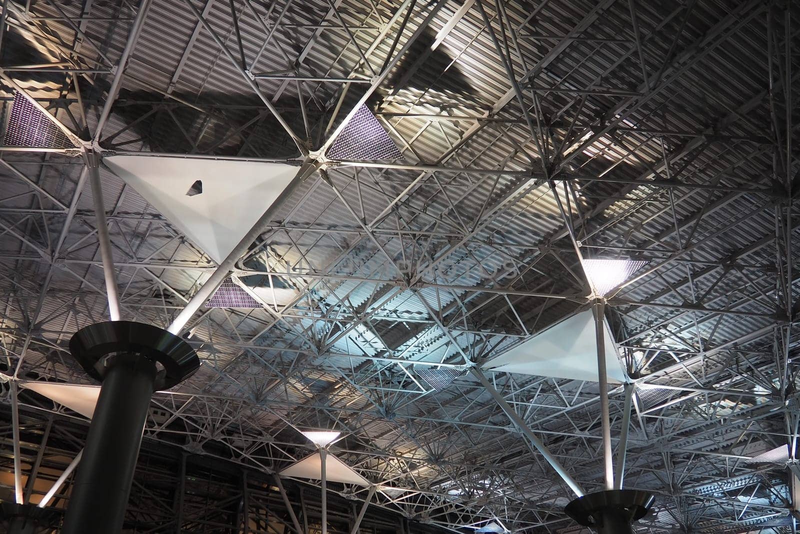 Metal structures under the ceiling. Decorative details of the airport ceiling . Concrete beams, glass windows and metal elements as public building interior design. Abstract avant-garde architecture