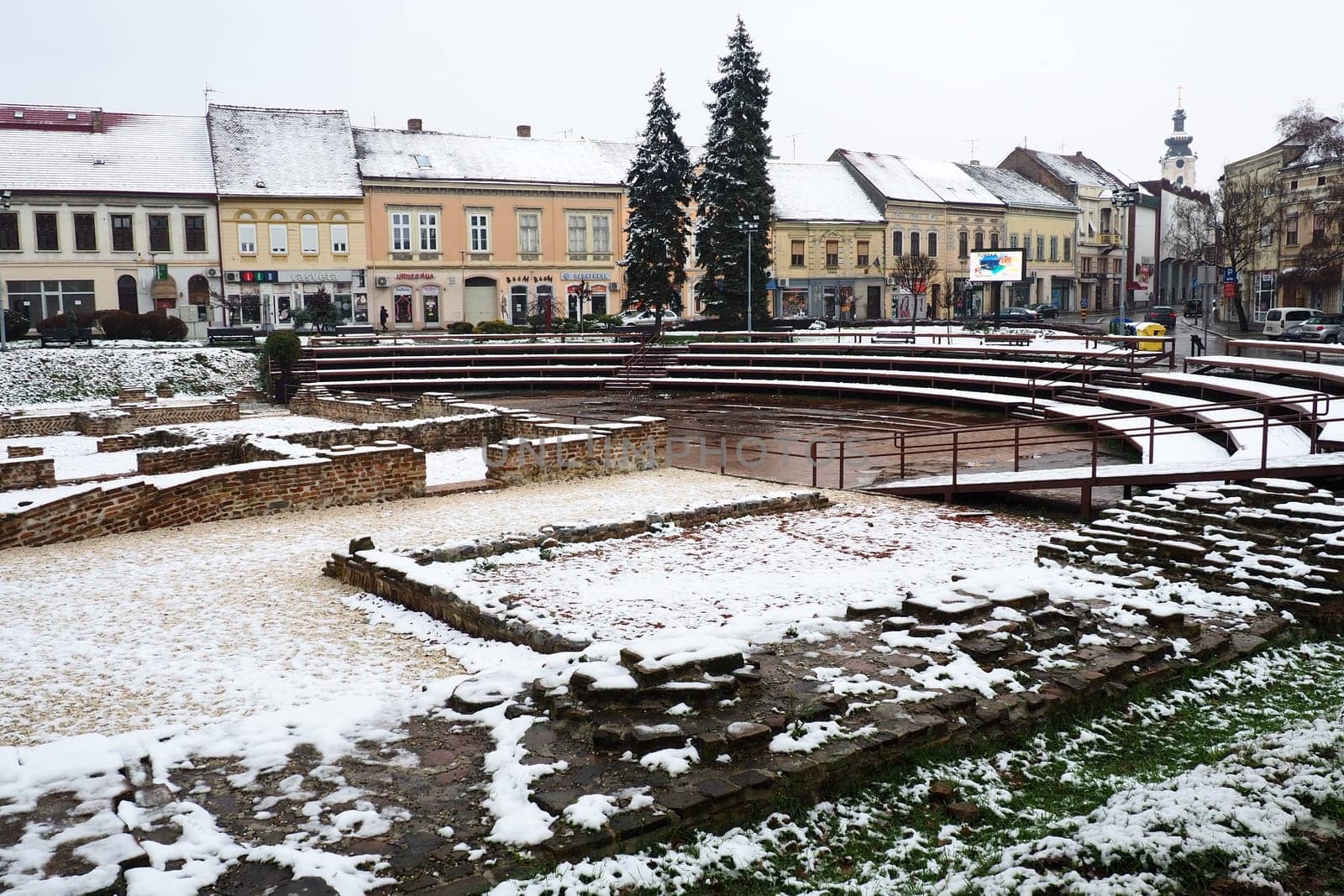 Sremska Mitrovica Serbia 01.27.2023 Snowfall in the city. Zhitni trg historical square. Ancient multi-colored buildings and excavations of Roman times. Weather forecast. Day winter. Cultural heritage