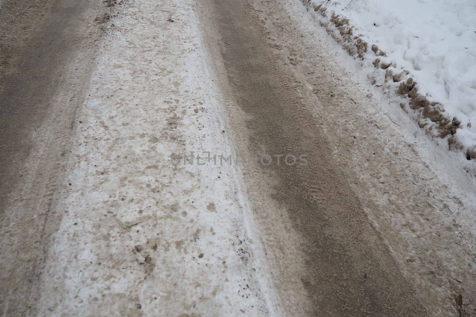 Snowdrifts on the side of the road. Bad weather and traffic. Snow on asphalt. Difficult driving conditions. Winter slush on the road. Wet weather, freezing temperatures. Weather forecast ice and snow.