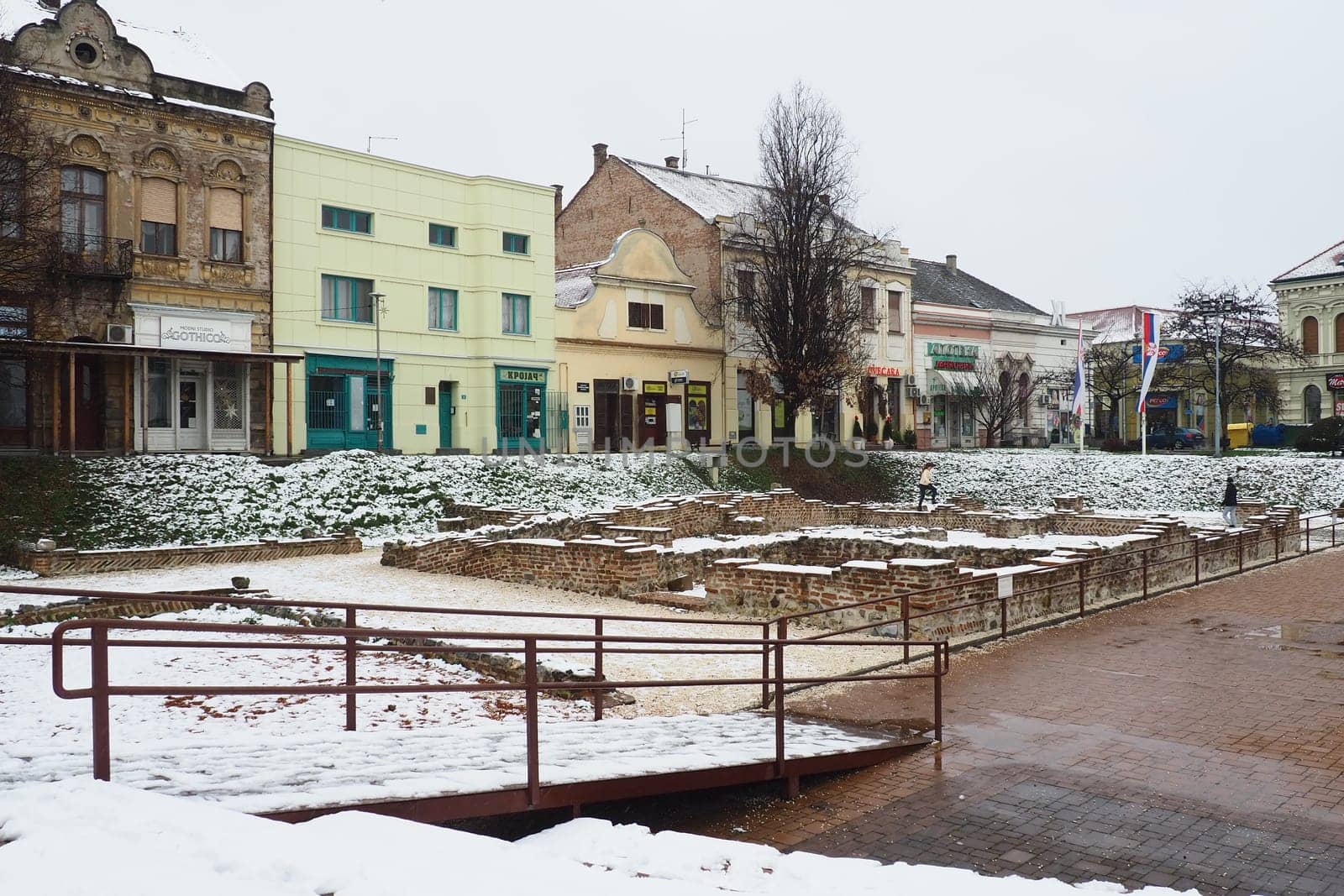 Sremska Mitrovica Serbia 01.27.2023 Snowfall in the city. Zhitni trg historical square. Ancient multi-colored buildings and excavations of Roman times. Weather forecast. Day winter. Cultural heritage