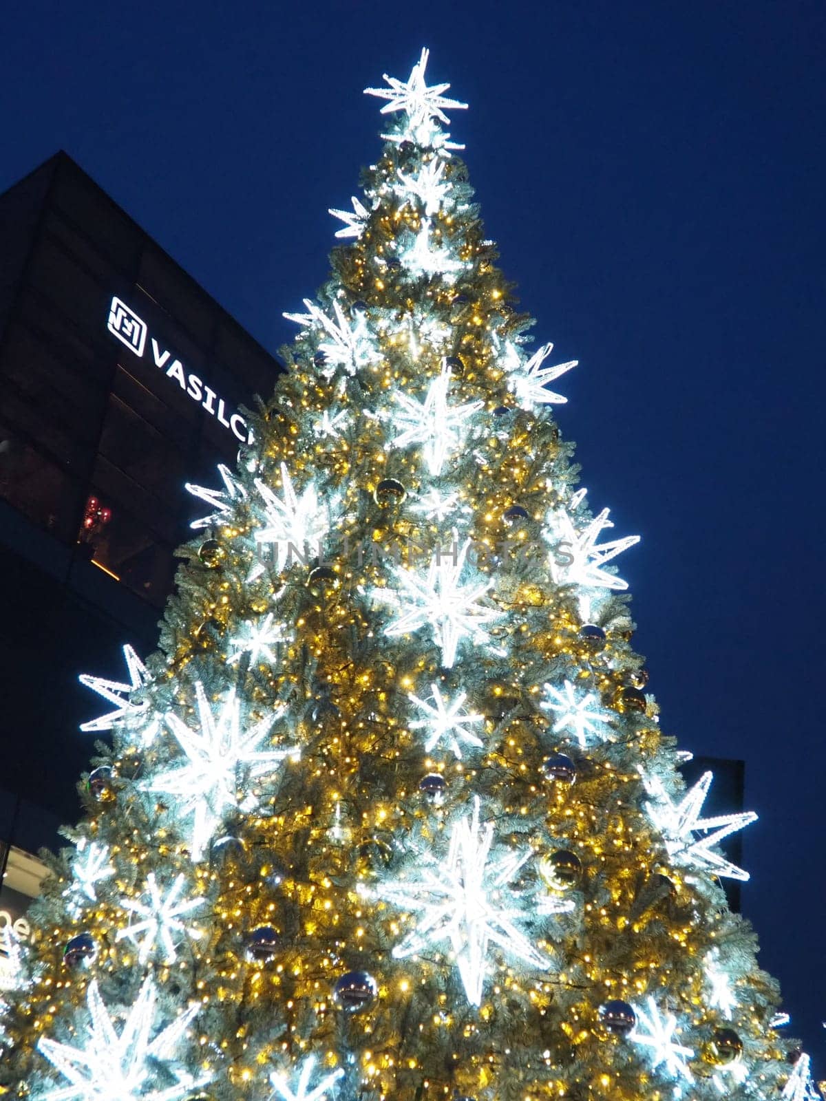 Moscow, Russia, January 17, 2023 Street Christmas tree with snowflakes and festive balls. Metro Yugo-Zapadnaya. Christmas decorations in front of the mall. Silver stars, snowflakes and golden garlands