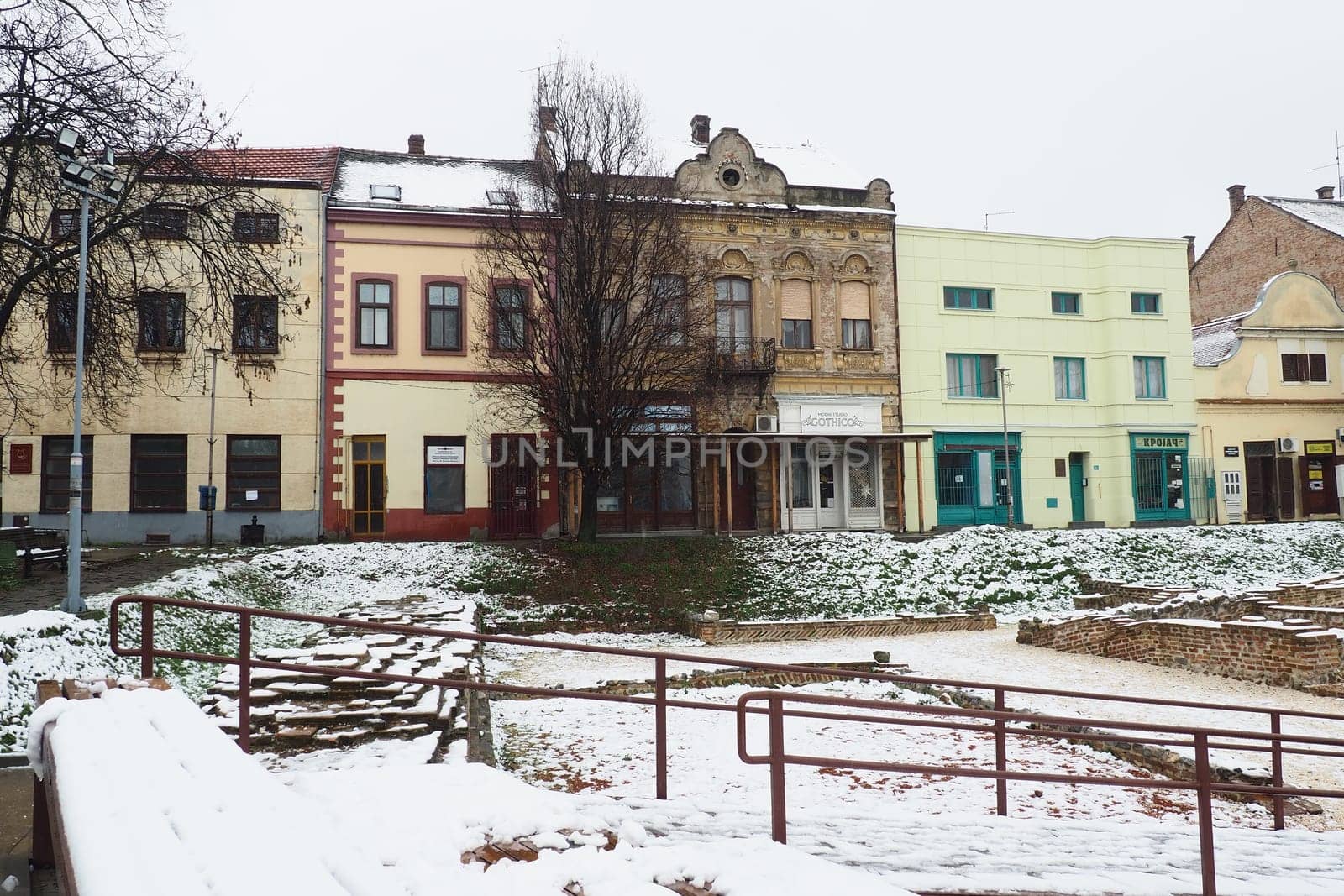 Sremska Mitrovica Serbia 01.27.2023 Snowfall in the city. Zhitni trg historical square. Ancient multi-colored buildings and excavations of Roman times. Weather forecast. Day winter. Cultural heritage