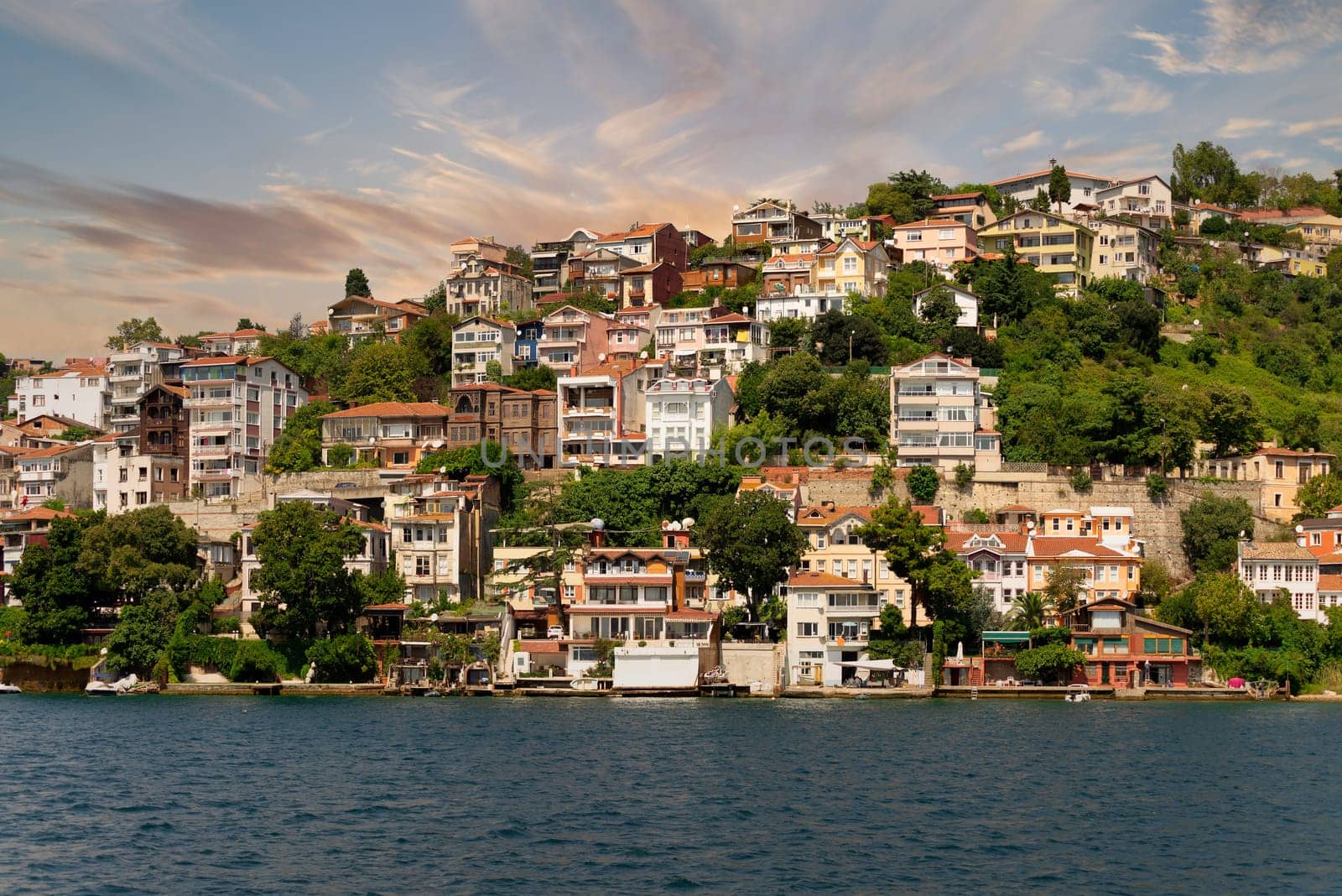 View from the sea of the green mountains of the Europian side of Bosphorus strait, with traditional houses and dense trees in a summer day before sunset, Istanbul, Turkey