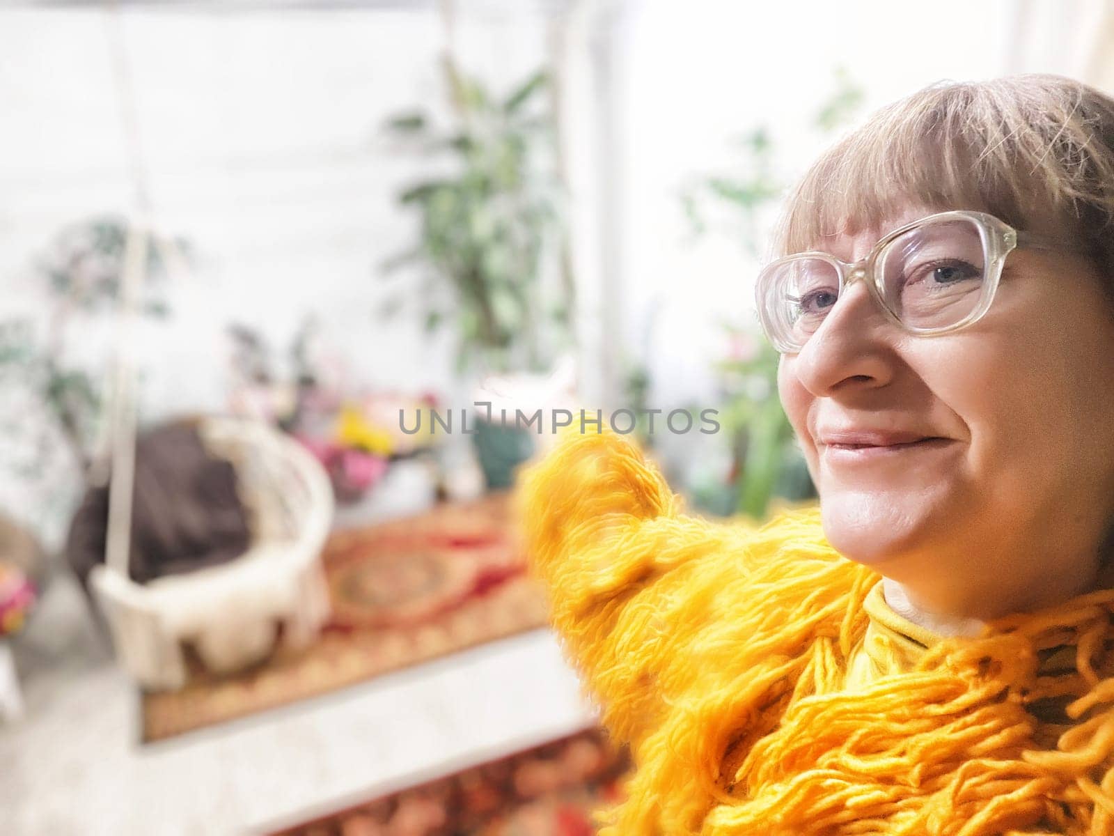 A mature blonde woman with glasses shows off her charming indoor garden during a blogging adventure.