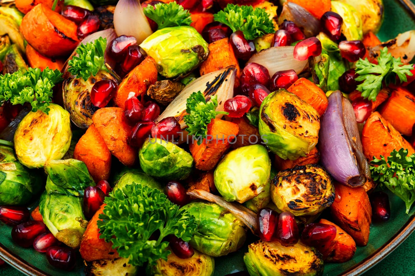 Salad with Brussels sprouts, carrots, with parsley and pomegranate seeds. Healthy vegetarian food
