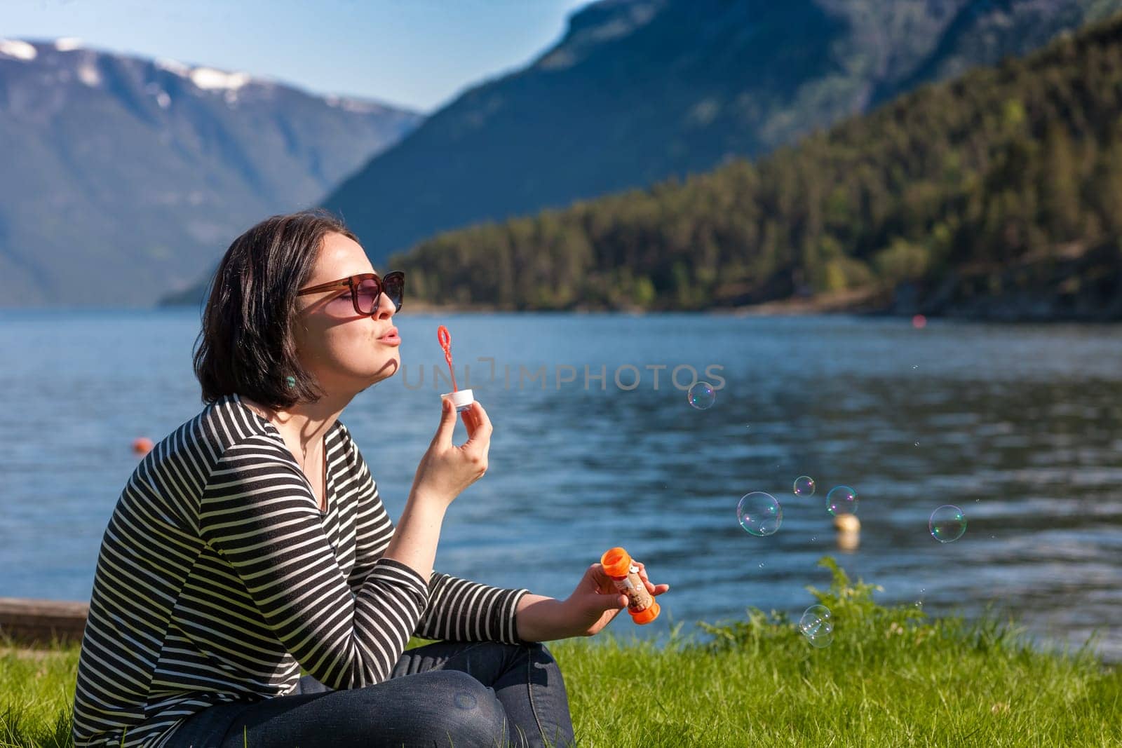 scenic landscapes of the northern Norwegian fjords in spring .The girl is blowing bubbles