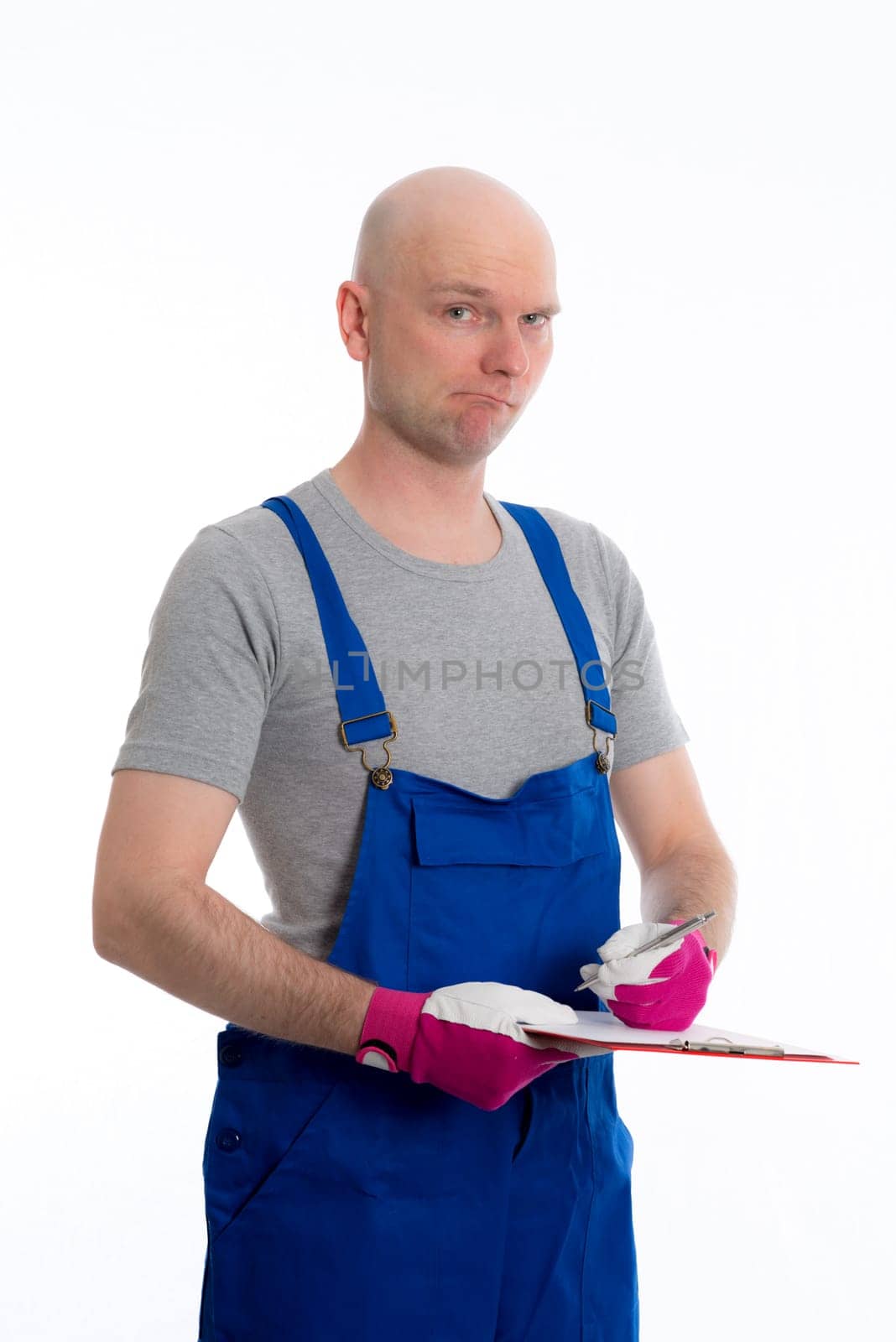 young workman in blue dungarees with clipboard in front of white background