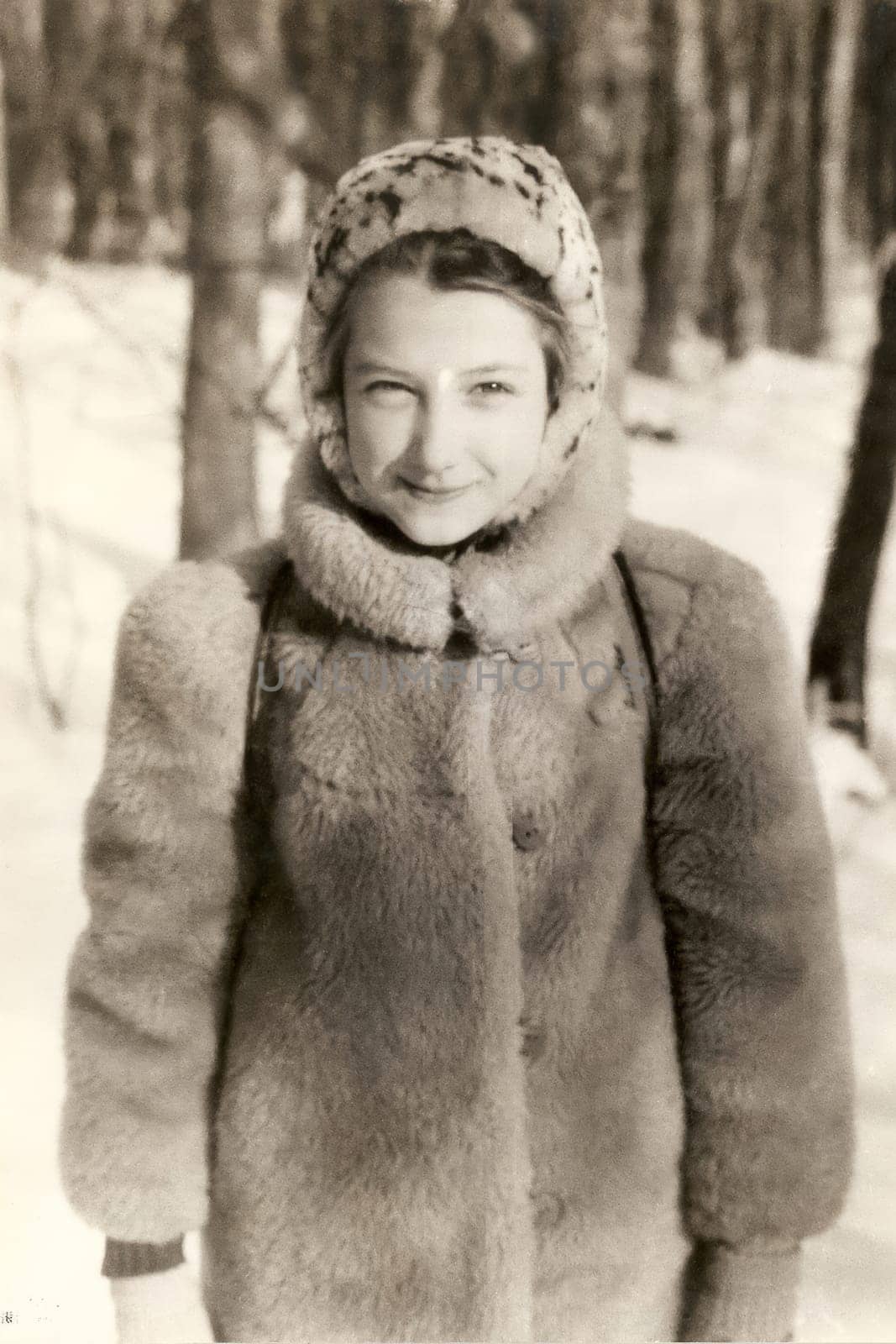 Portrait of a Soviet girl in a fur coat and a fur hat. Old vintage sepia photo taken in the USSR in the 1991