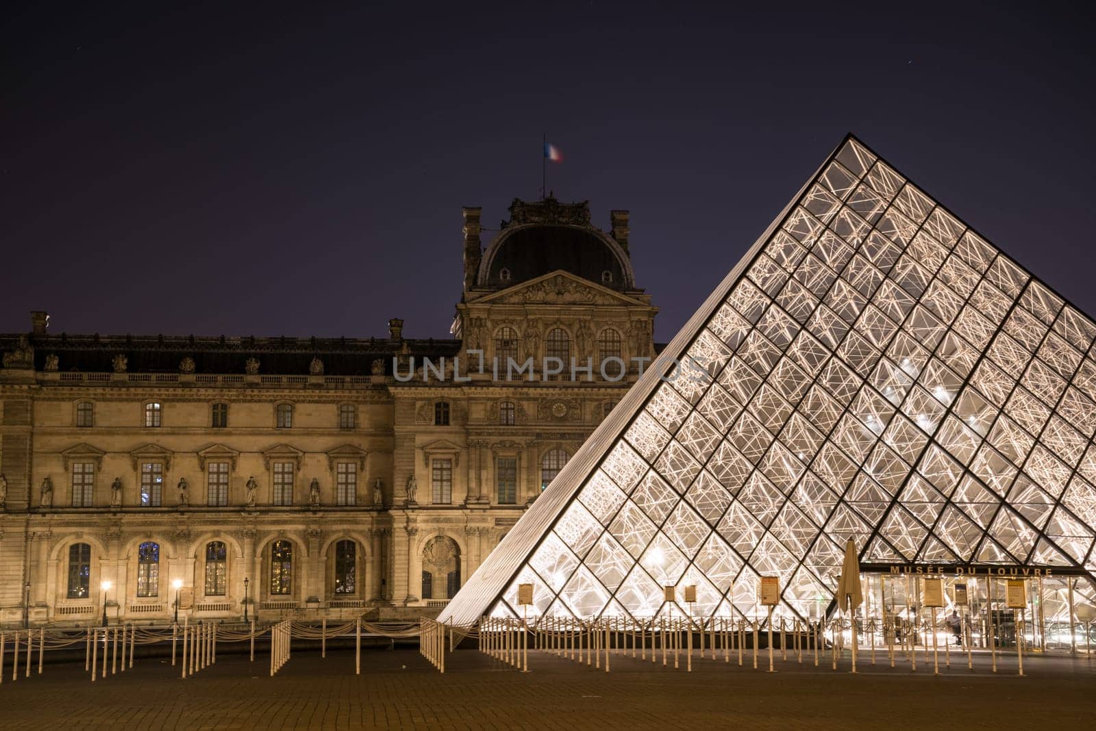 The famous Louvre Palace and its iconic glass pyramide at night, Paris, France
