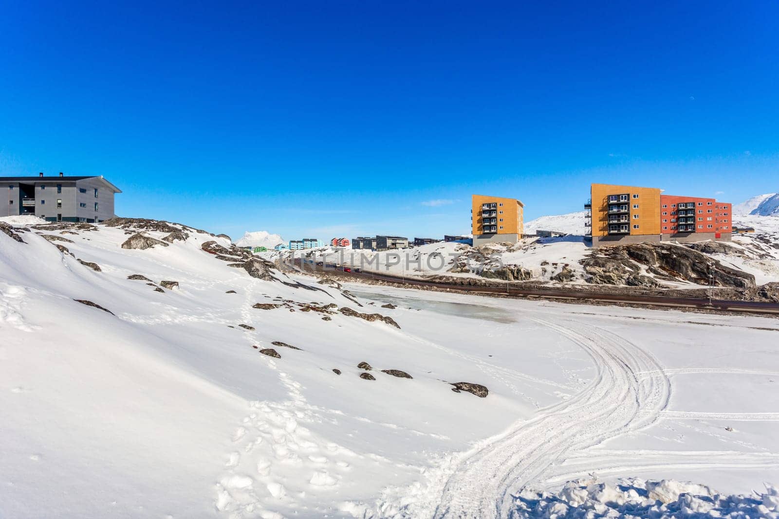 Greenlandic landscape with Inuit multistory houses of Nuuk city on the rocks with mountains in the background, Greenland