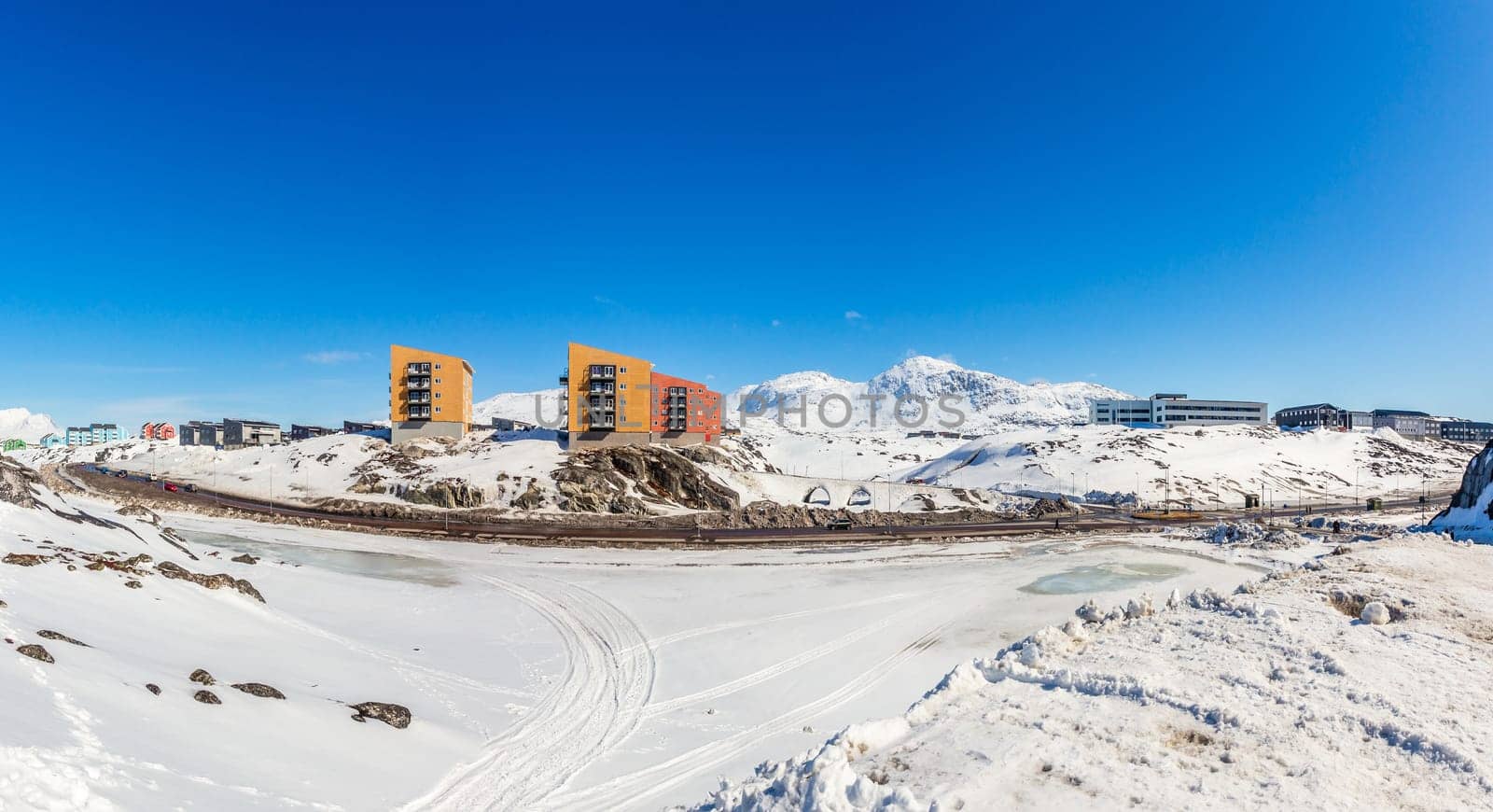 Greenlandic landscape with Inuit multistory houses of Nuuk city on the rocks with mountains in the background, Greenland
