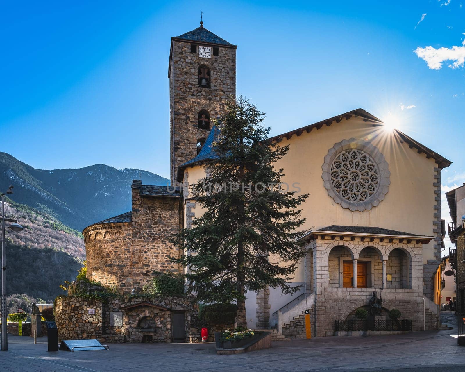 Beautiful, 11th century stone St. Esteve Church with sun star and Pyrenees Mountains in background, Andorra la Vella