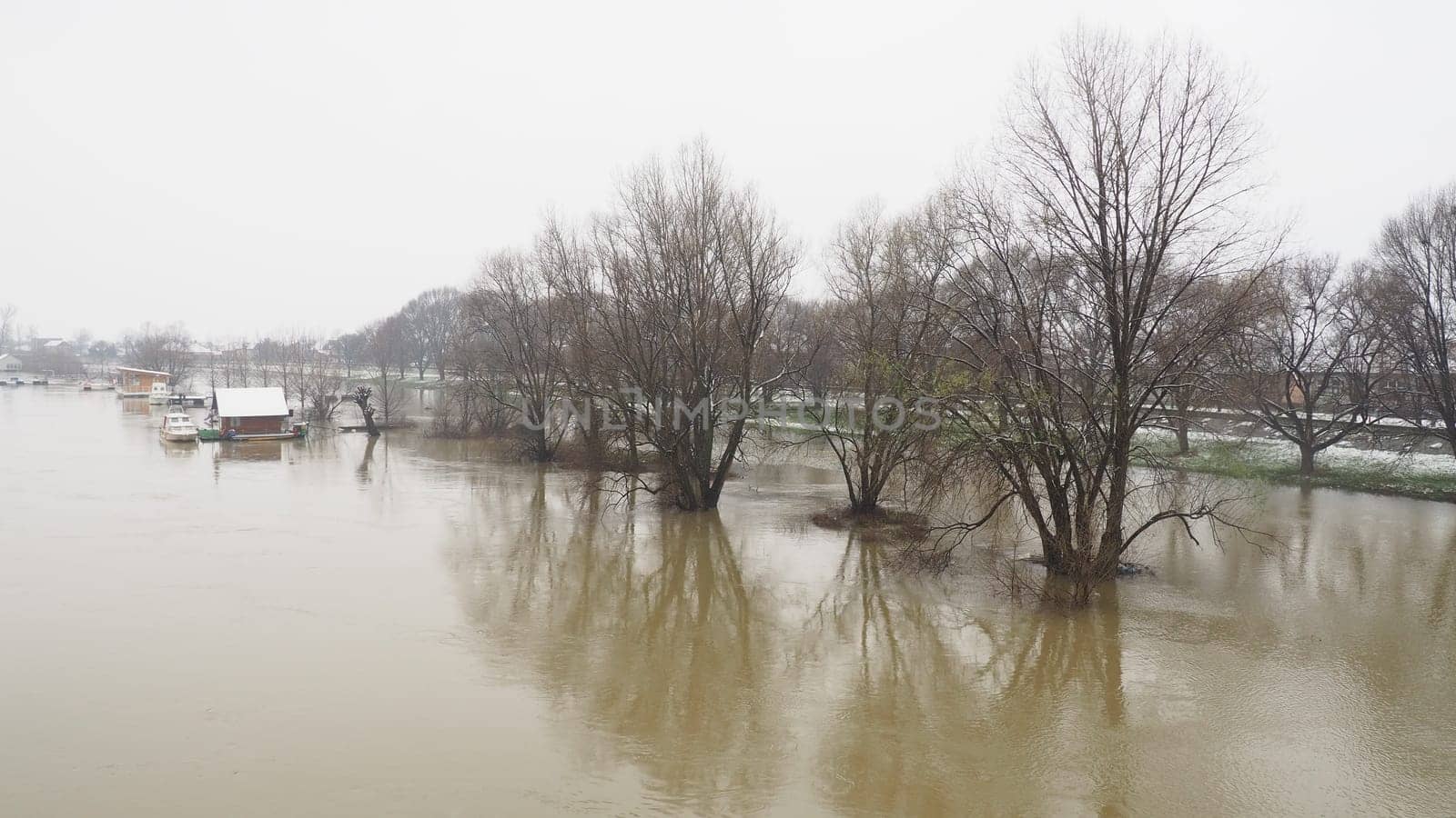 Macvanska Mitrovica, Serbia, 01/27/2023 The bridge over the Sava River. Flooding after heavy rains and snowmelt. A swift flow of muddy water. Trees, boats and piers in the water. Machva in winter