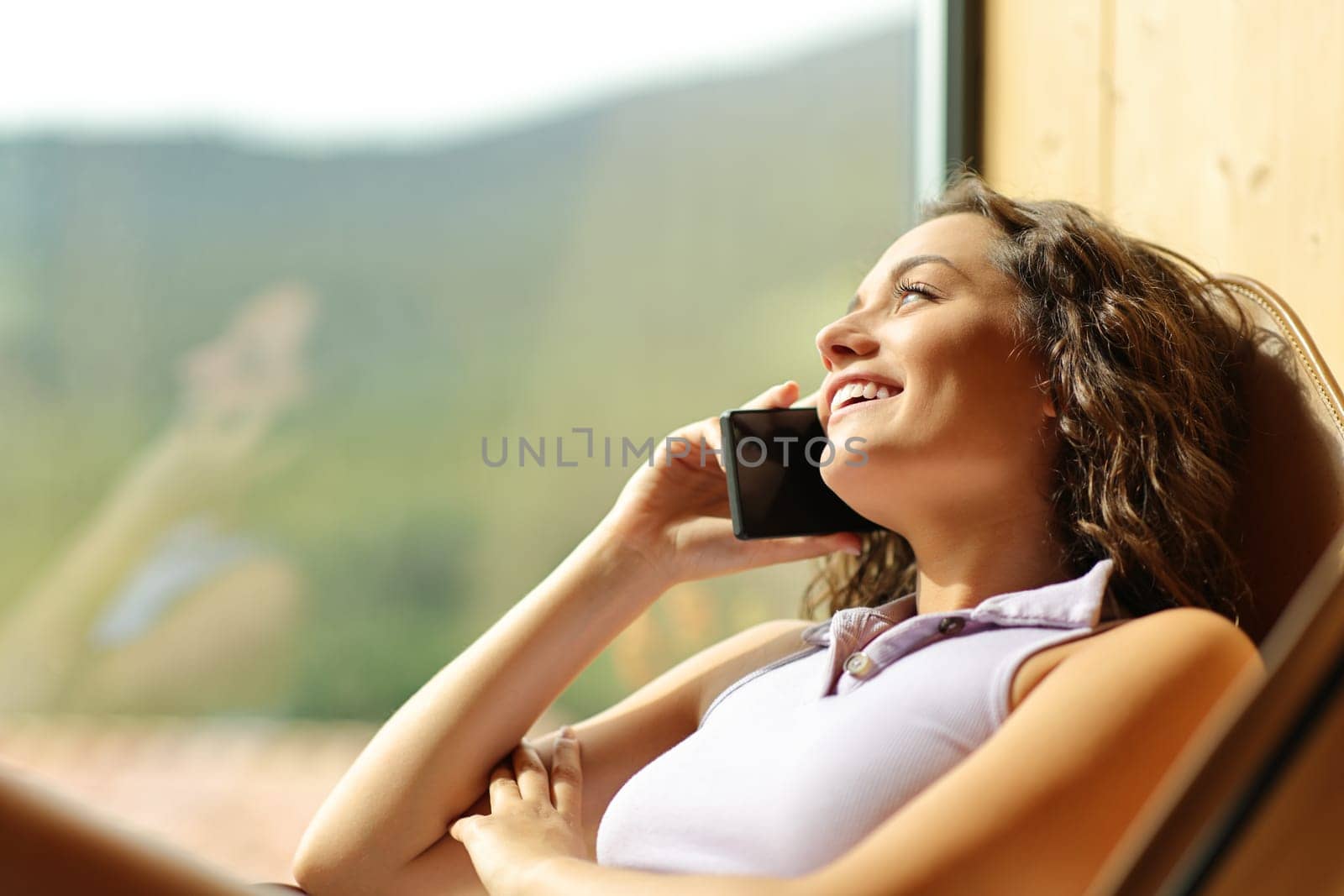 Happy woman on a chair talking on phone smiling
