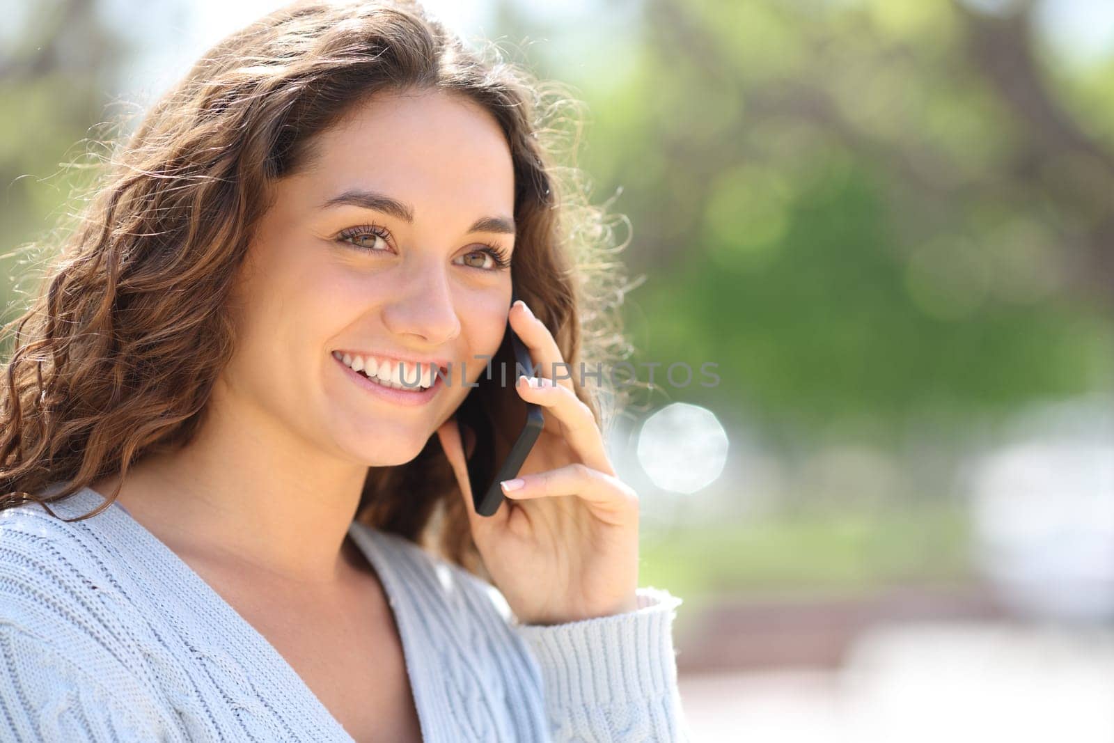 Happy woman talks on phone walking outside